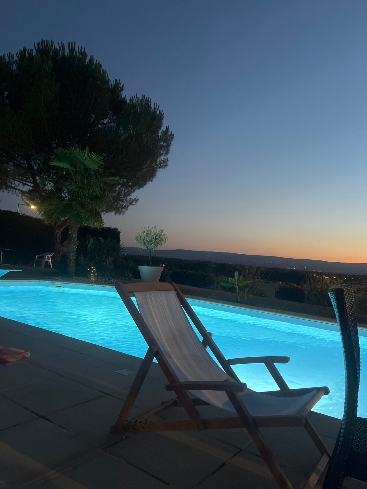 Evening poolside relaxation at a lit outdoor pool in Saint-Galmier