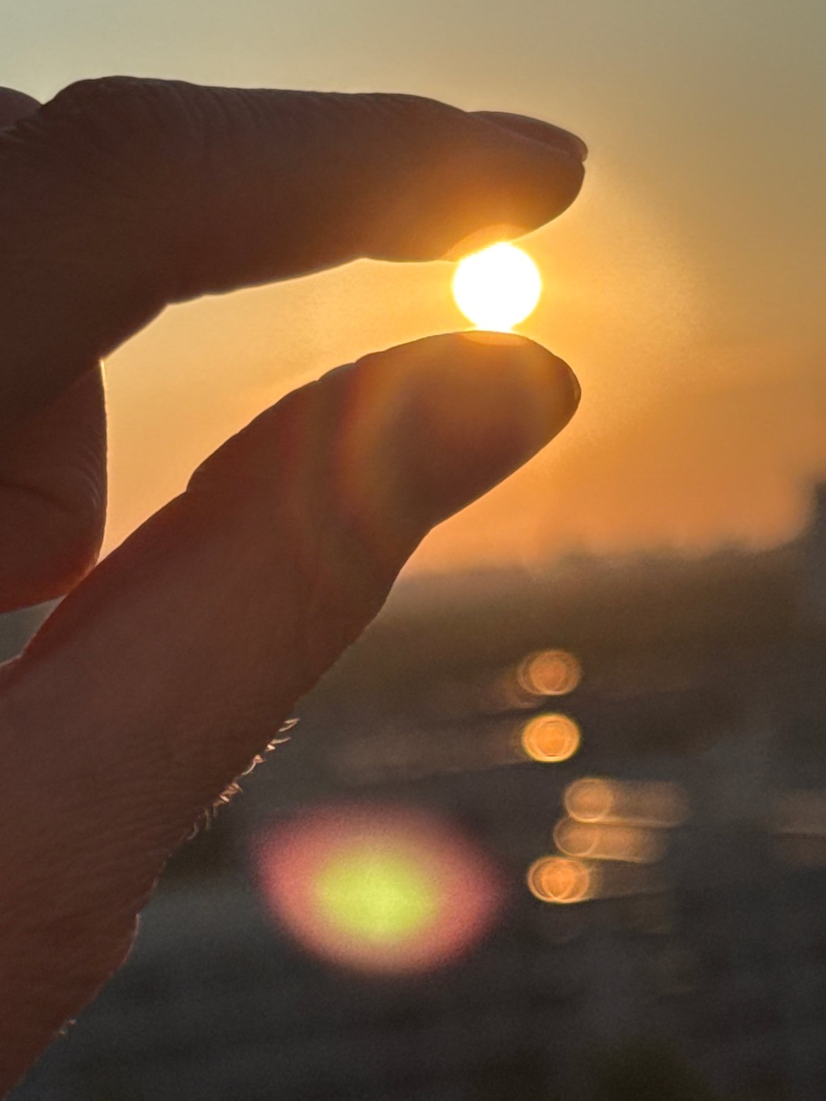 Hands framing a setting sun in Russia, two ways