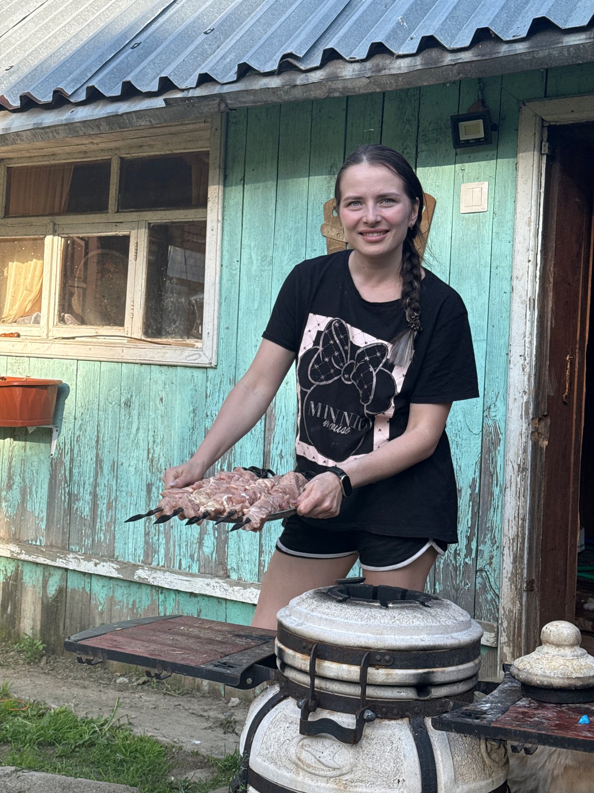 Woman prepares barbecue with dogs in Russian village backyard