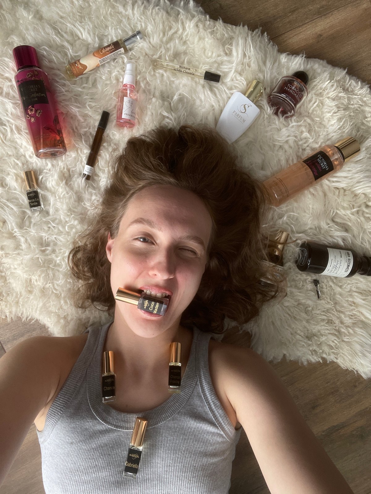 Woman creates artistic perfume bottle display on bedroom floor