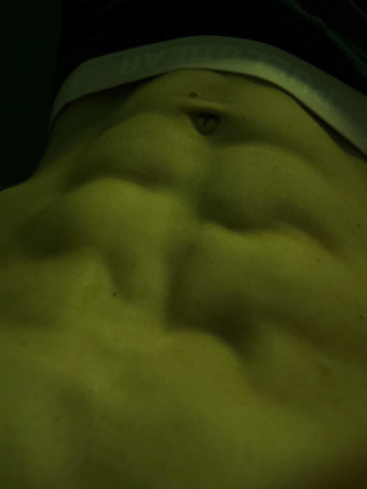 Close-up of defined abs in dramatic low-light setting