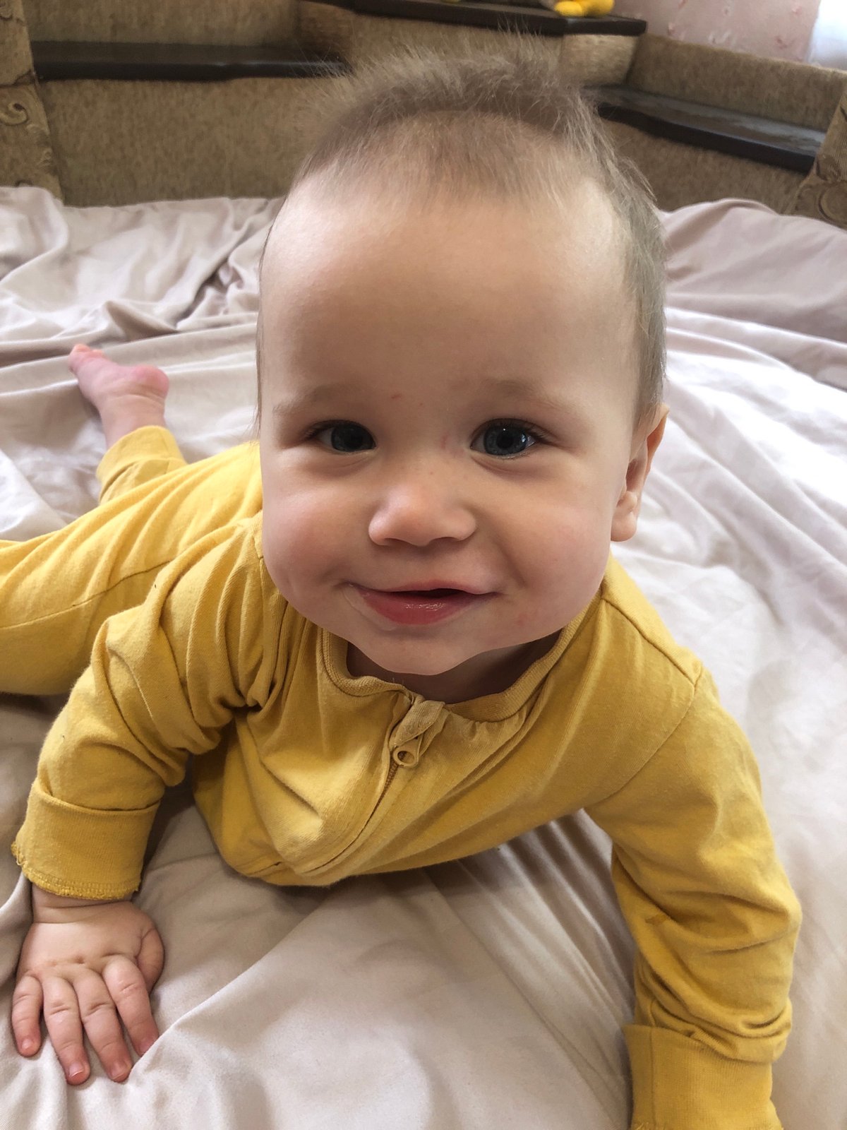 Baby in yellow pajamas resting on a comforter in Radomyshl