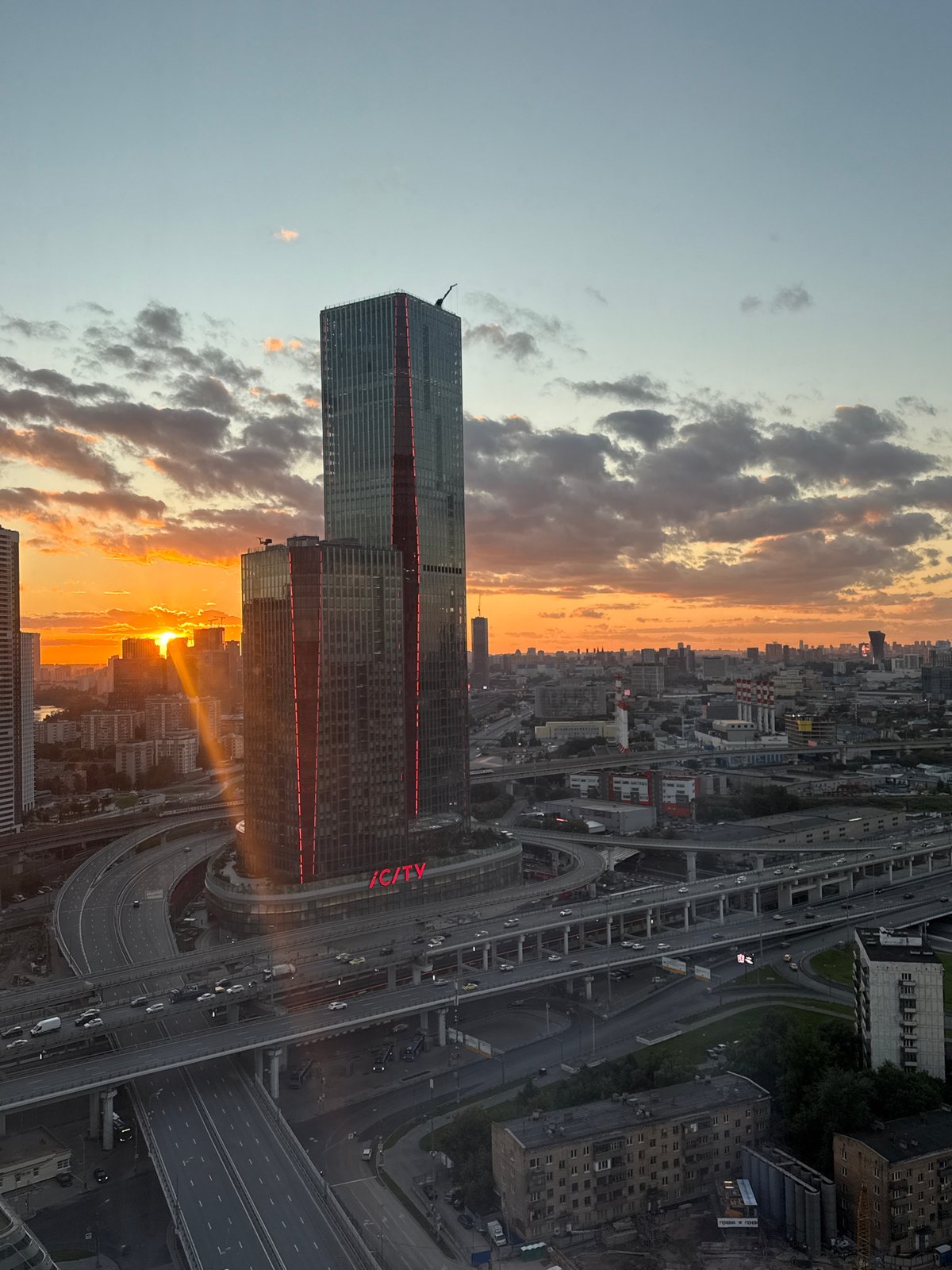 Skyscraper with glowing '/CITY' logo at sunset