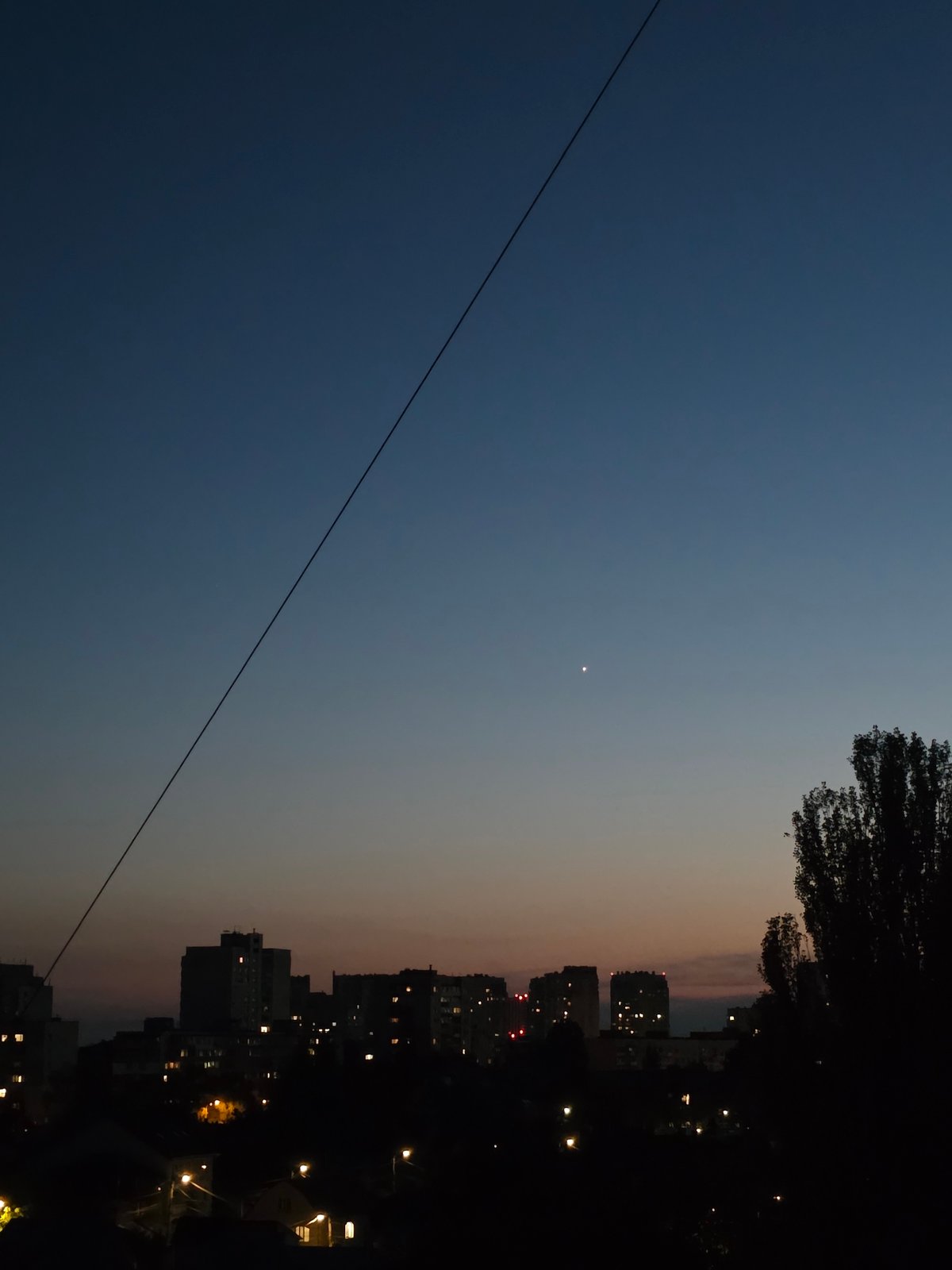 Aerial dusk-to-night drift over a residential neighborhood