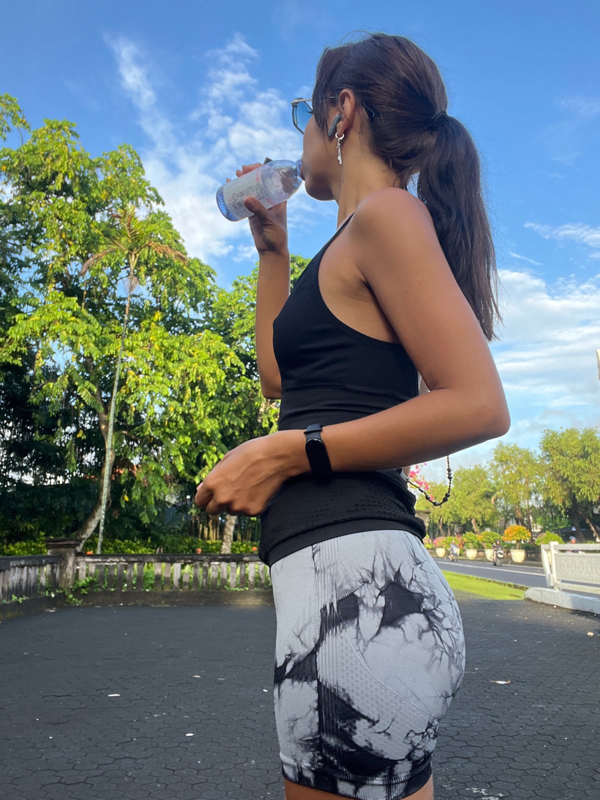 Woman takes water break on evening path in Kuta Selatan