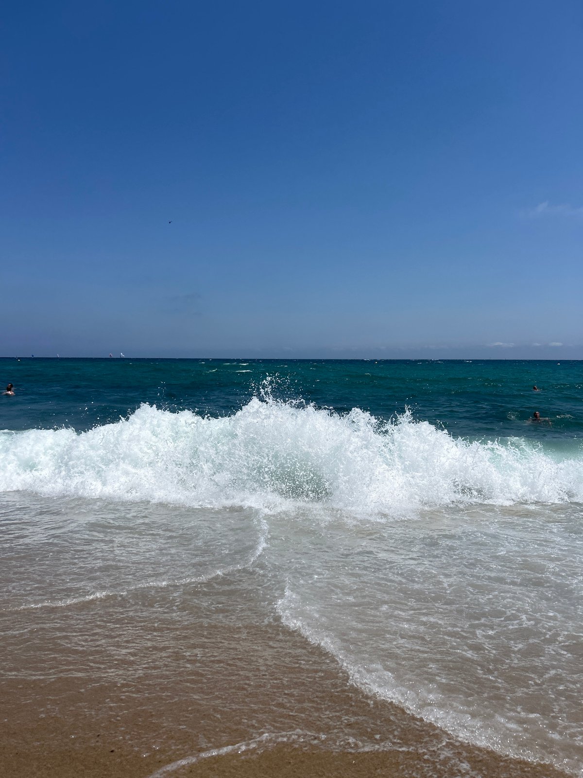 Waves breaking on a Barcelona beach, helicopter passing overhead