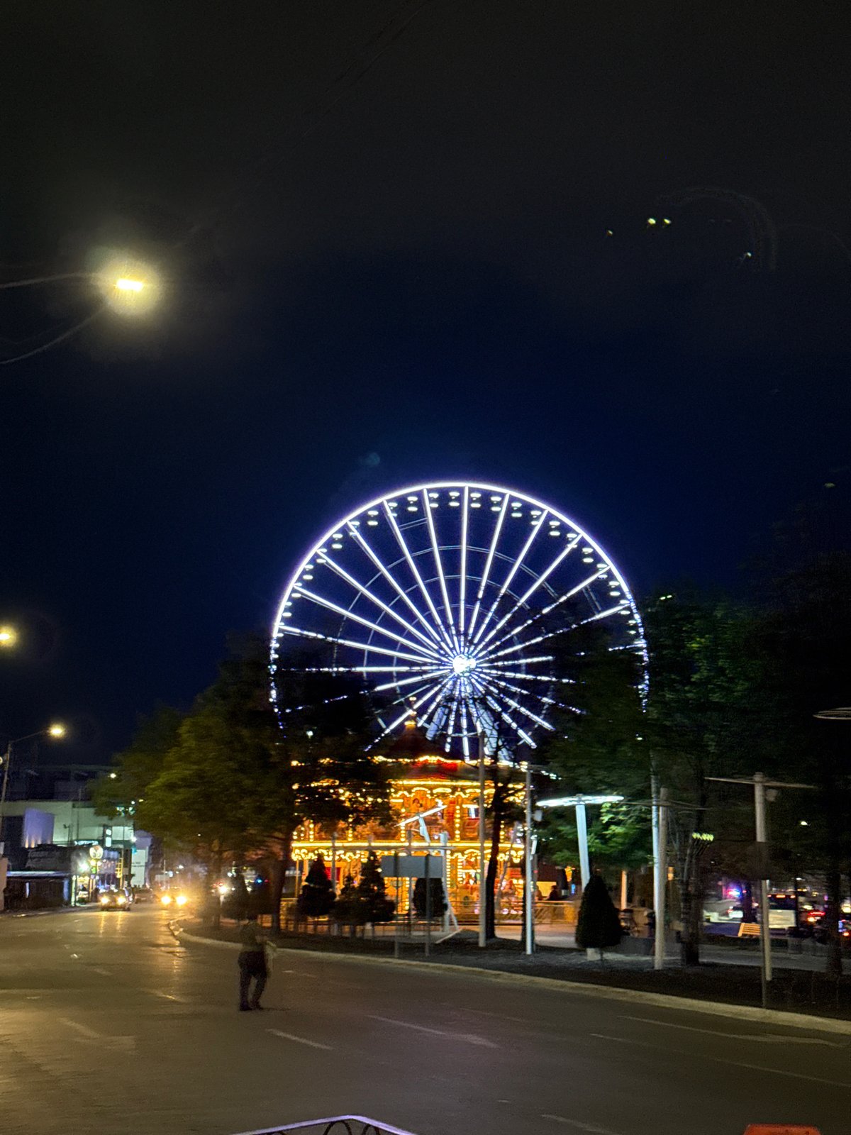 Night scenes captured around illuminated ferris wheel in Puebla
