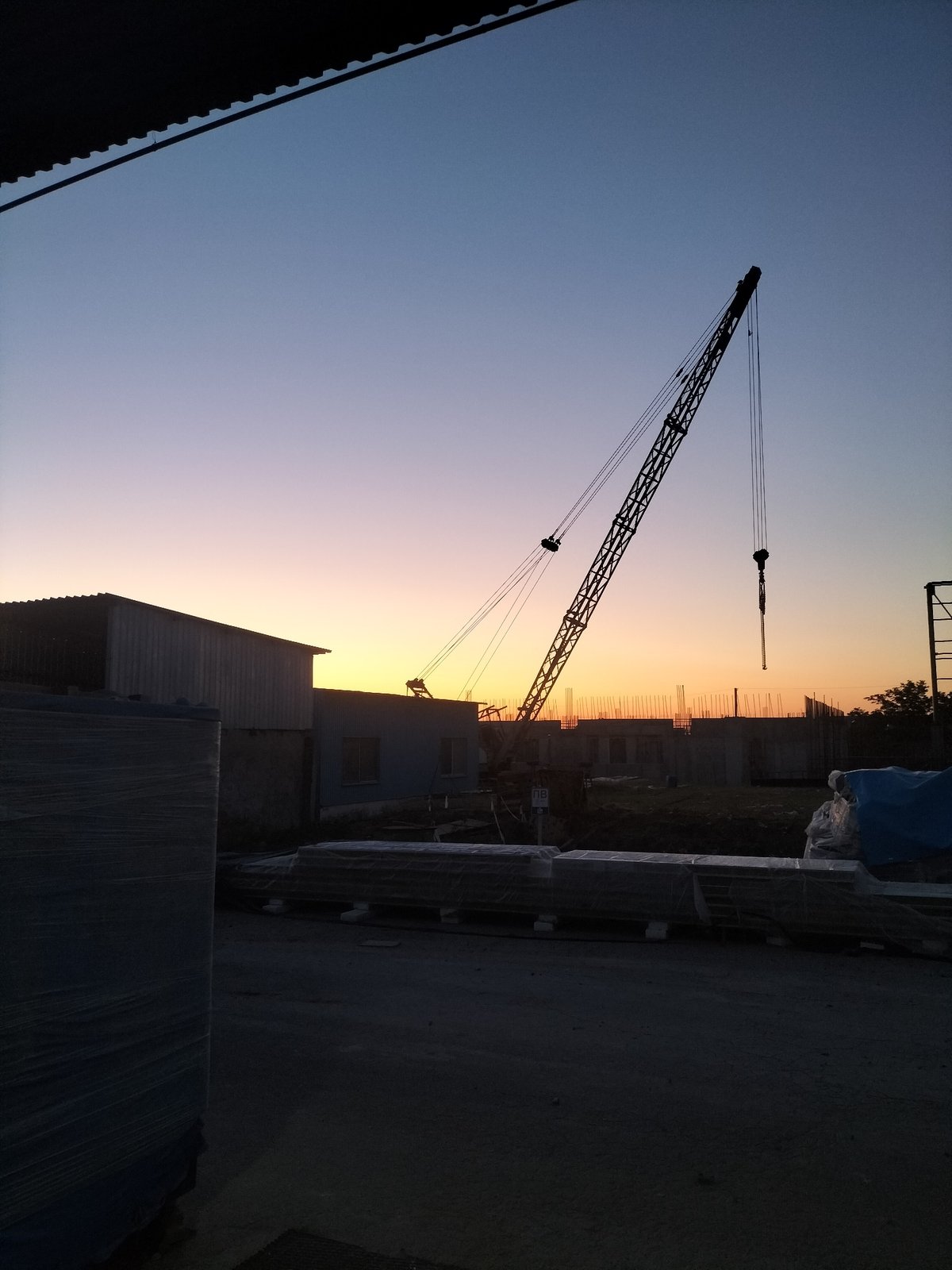 Tower crane silhouetted against a vivid dusk sky