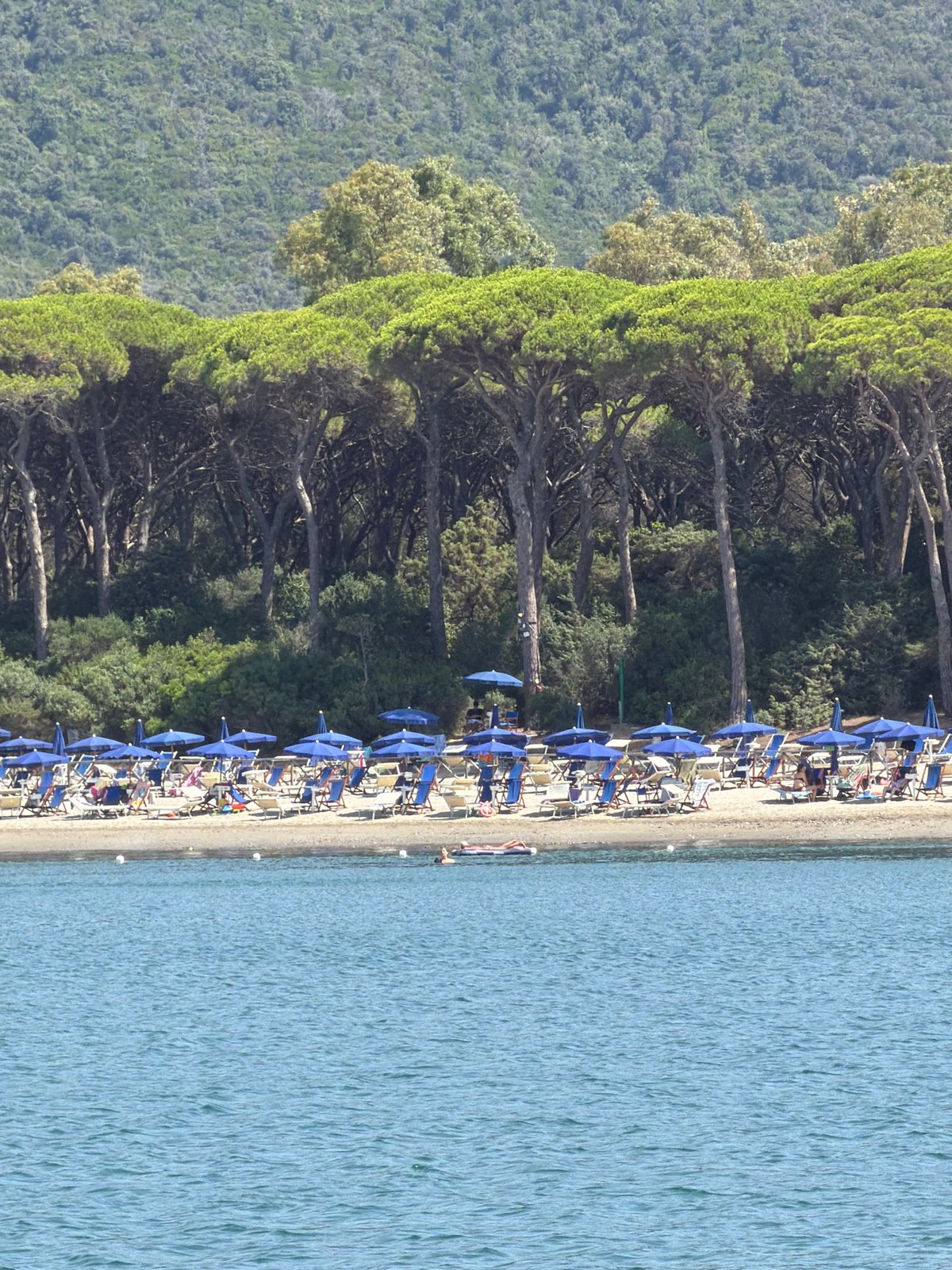 Beach day at Punta Ala: packed shore, snorkeling, anchored yacht