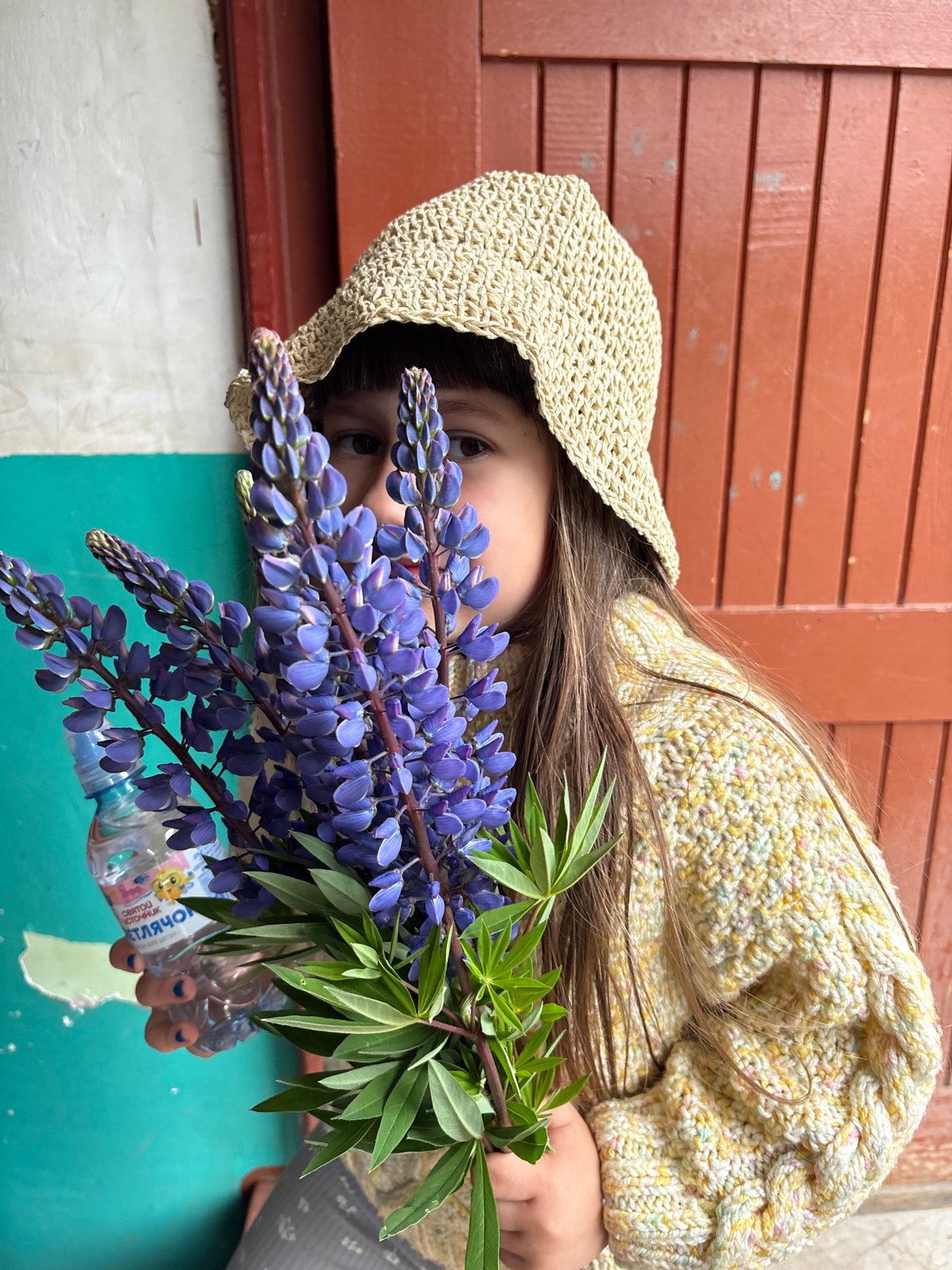 Child poses with purple flowers in Russian village