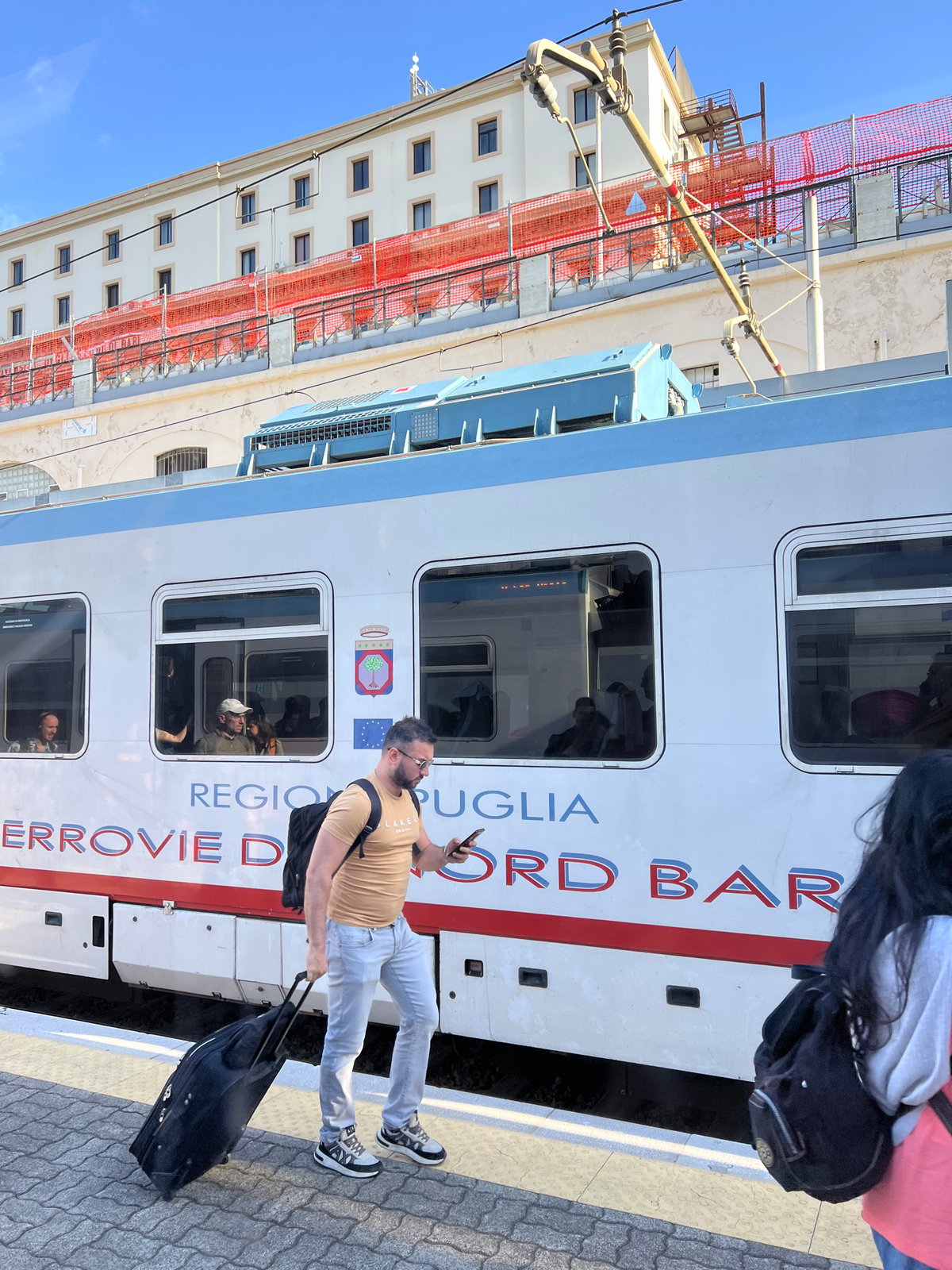 Man stands on sunny train platform in Bari, Italy