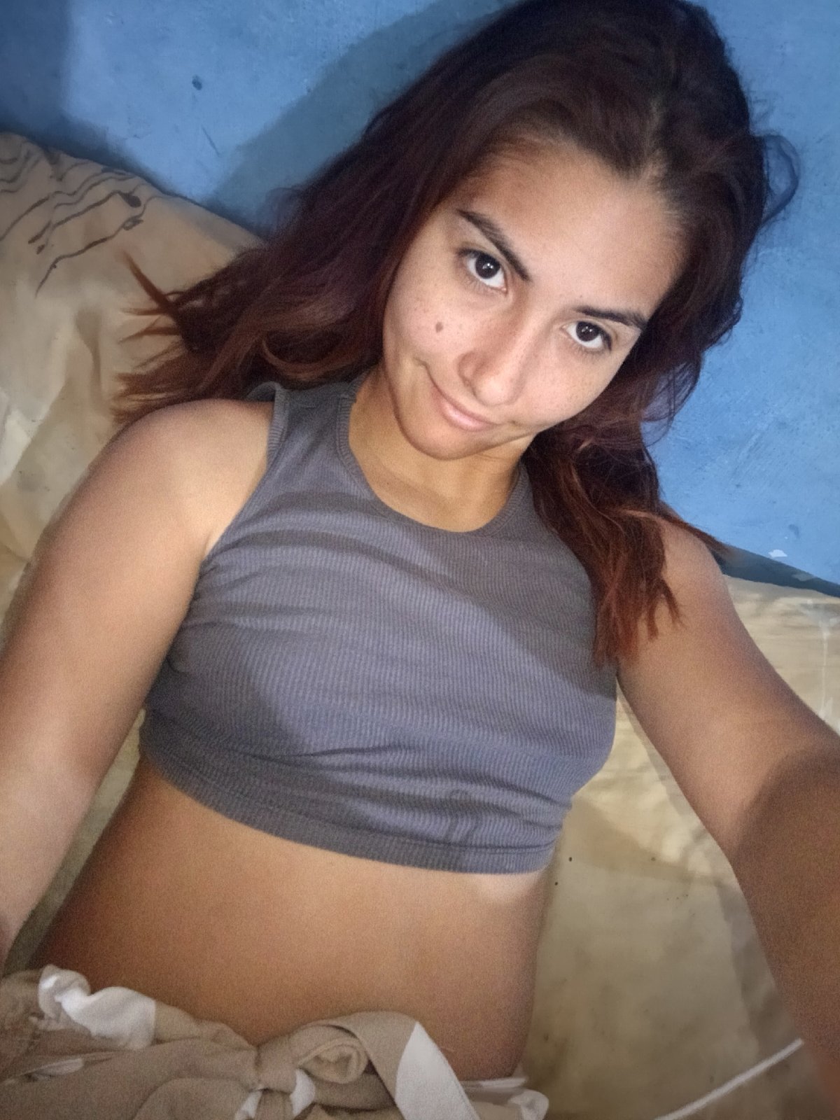 Woman documents casual afternoon with selfies in blue-walled bedroom