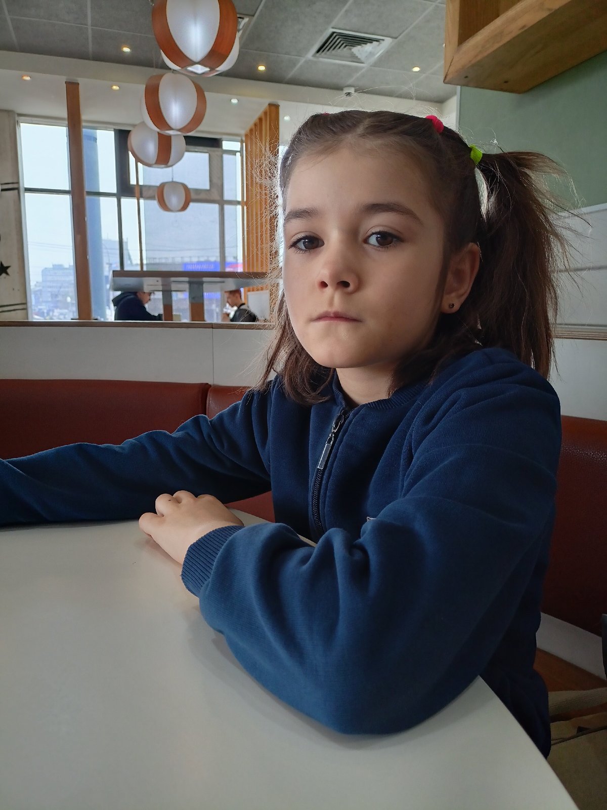 Girl in pigtails sits at indoor table