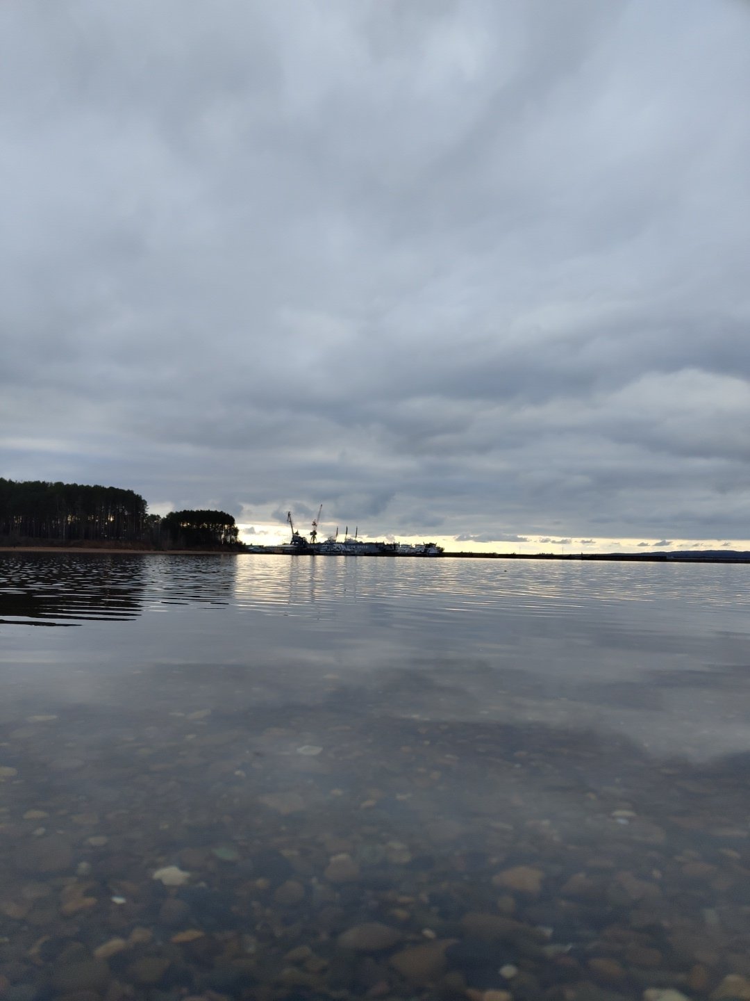 Child visits waterfront on overcast afternoon in Chaikovsky, Russia