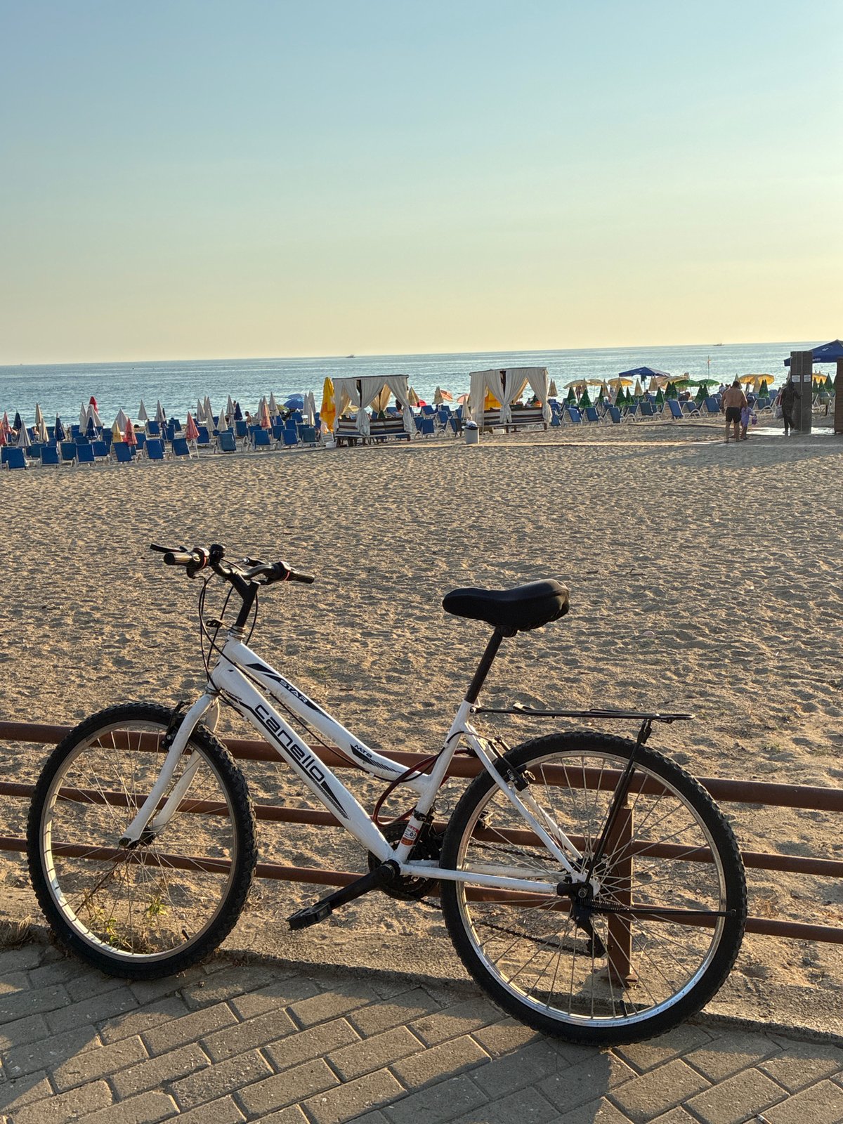 White bicycle parked along a sunny Alanya beach promenade