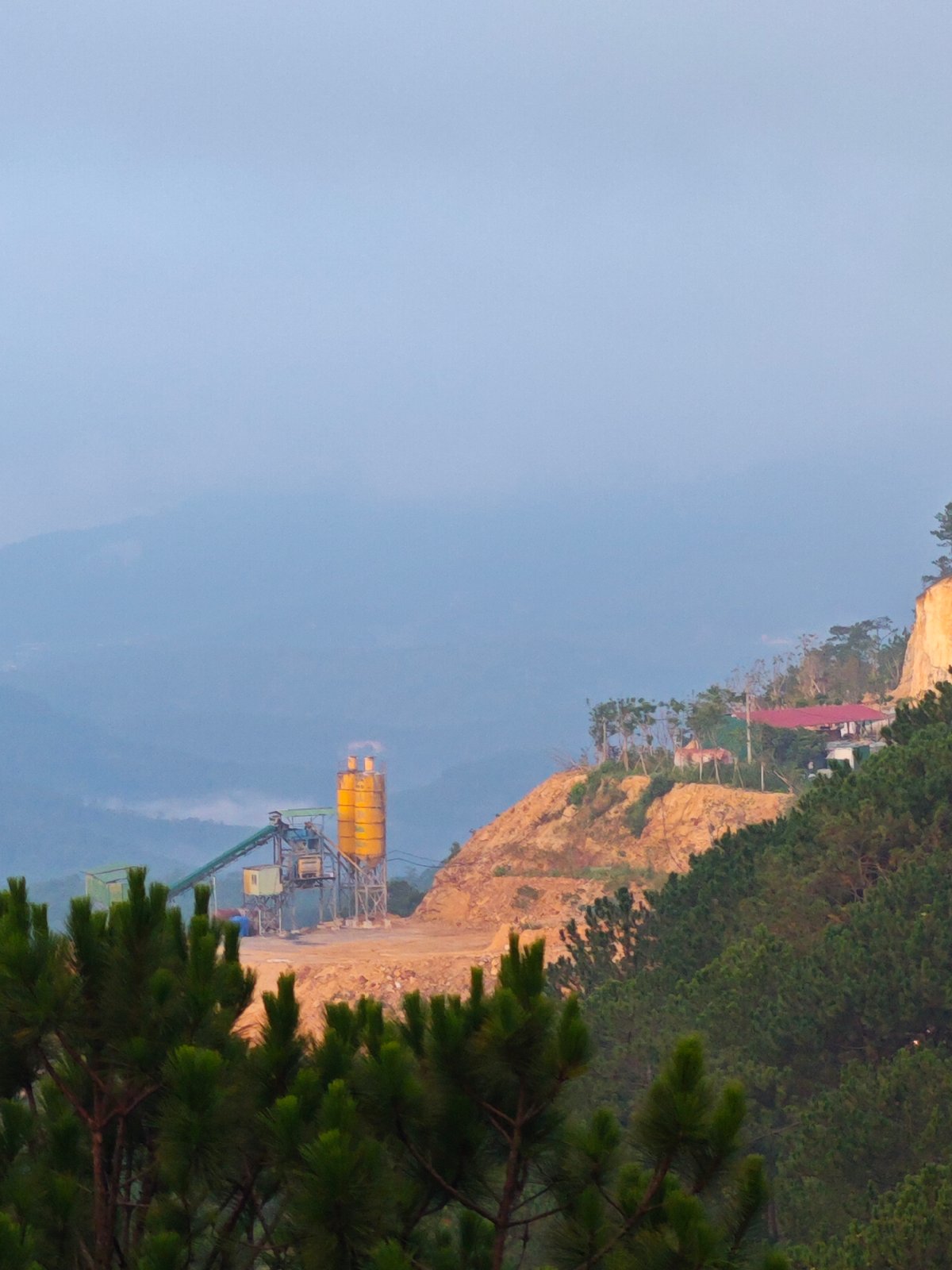 Greenhouses and concrete plant share a Vietnamese hillside valley