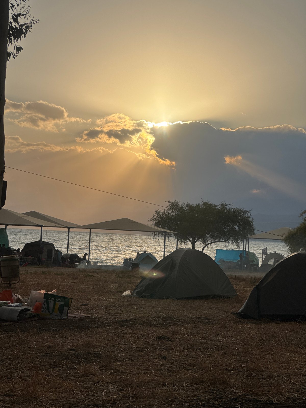 Campers gather at waterside campsite during sunset hours
