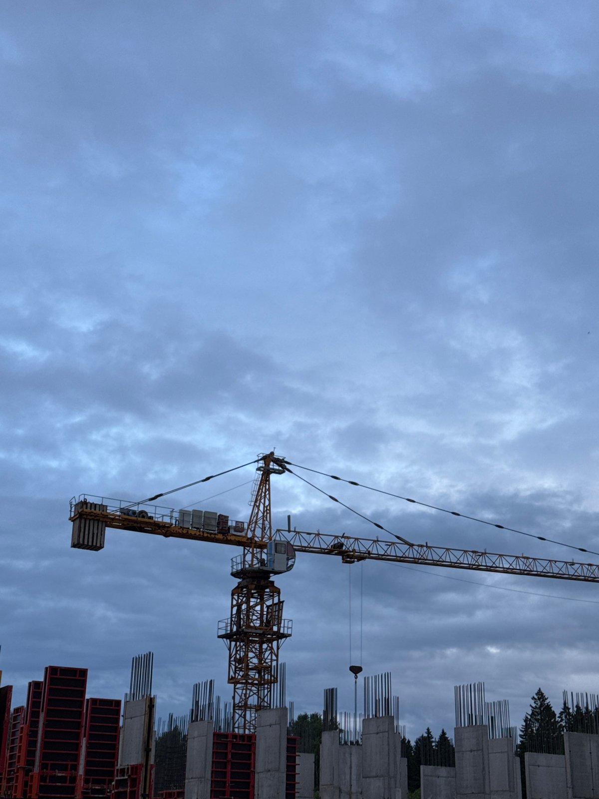 Adult carries child through Izhevsk construction site under overcast skies