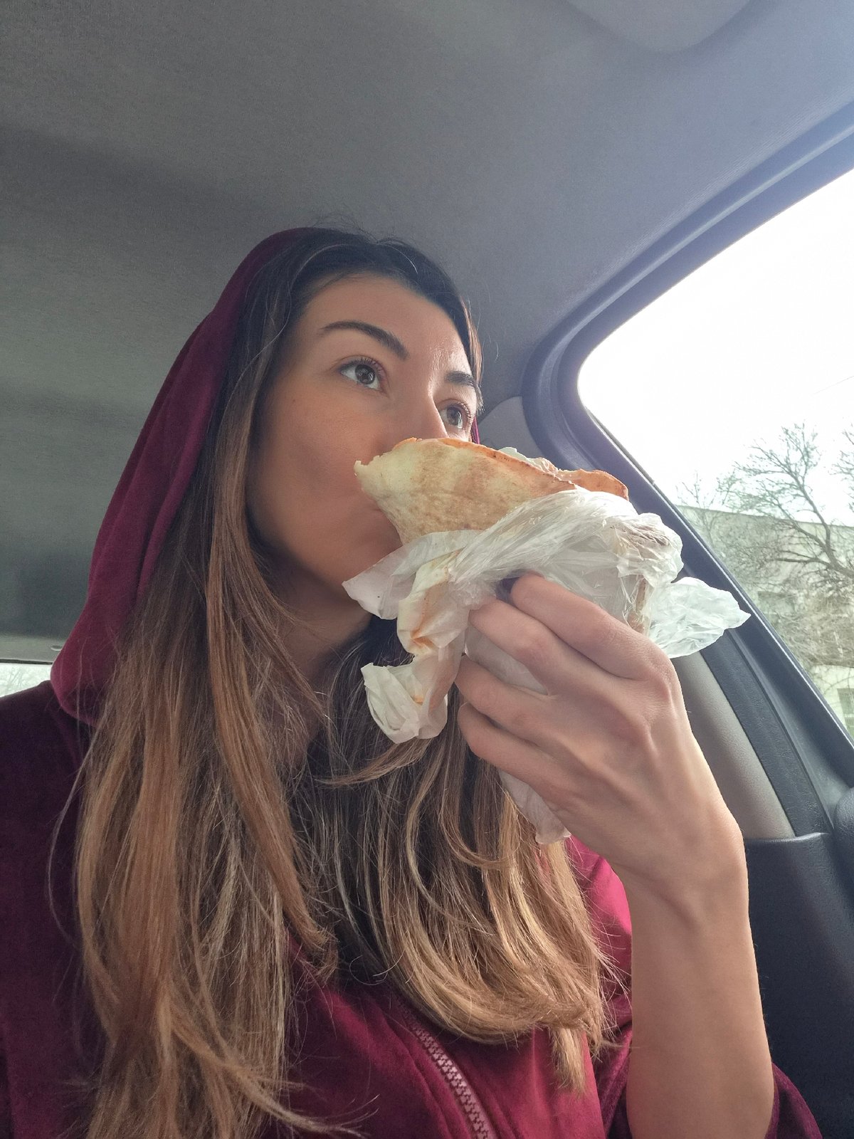 Woman eats shawarma sandwich in car in Plovdiv