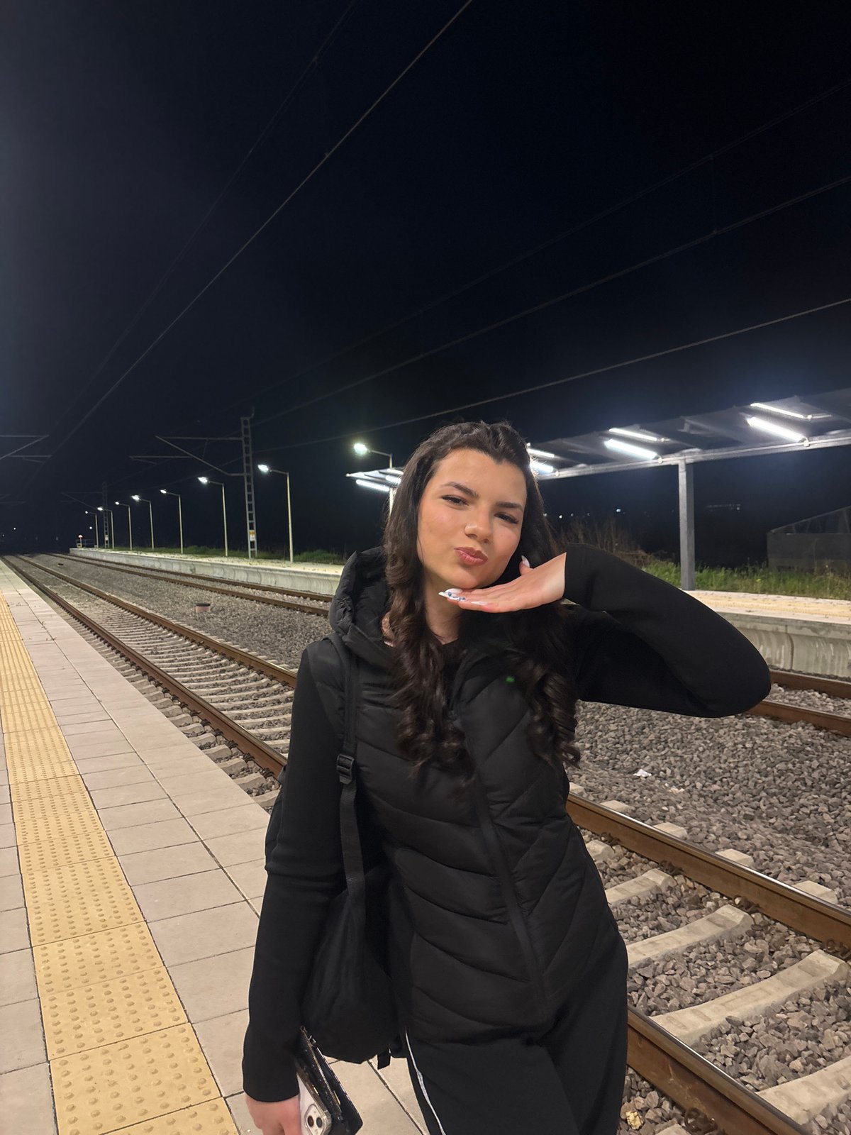 Woman poses playfully on Plovdiv train platform at night