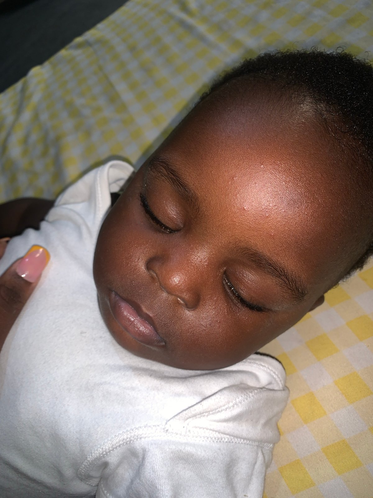 Baby sleeping peacefully, adult hand nearby in quiet moment