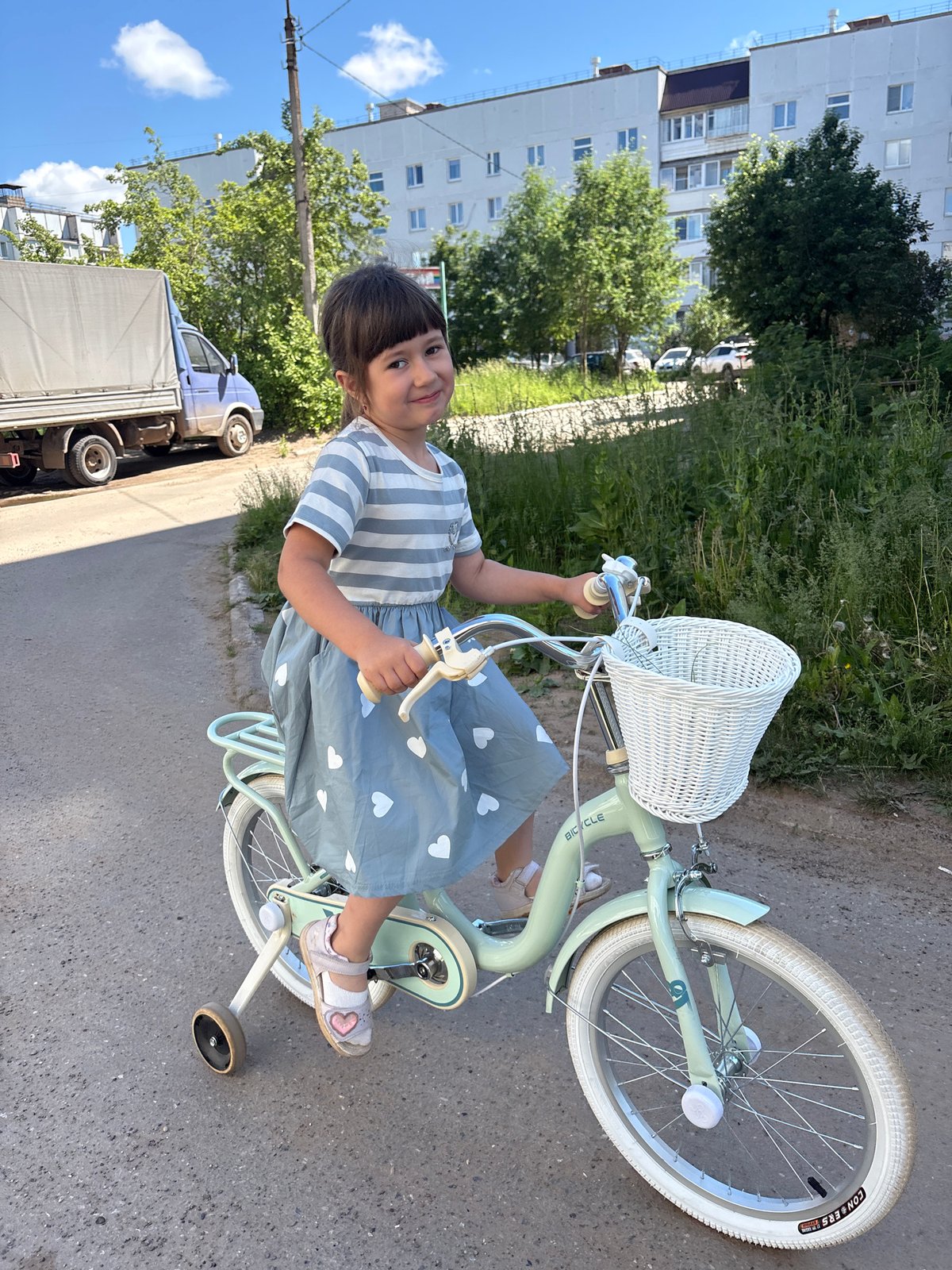 Child learns to ride bicycle with training wheels