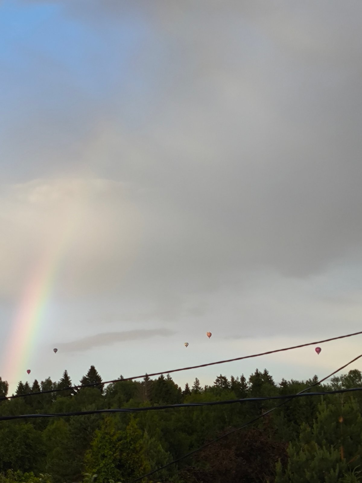 Rainbows and hot air balloons over a rural landscape