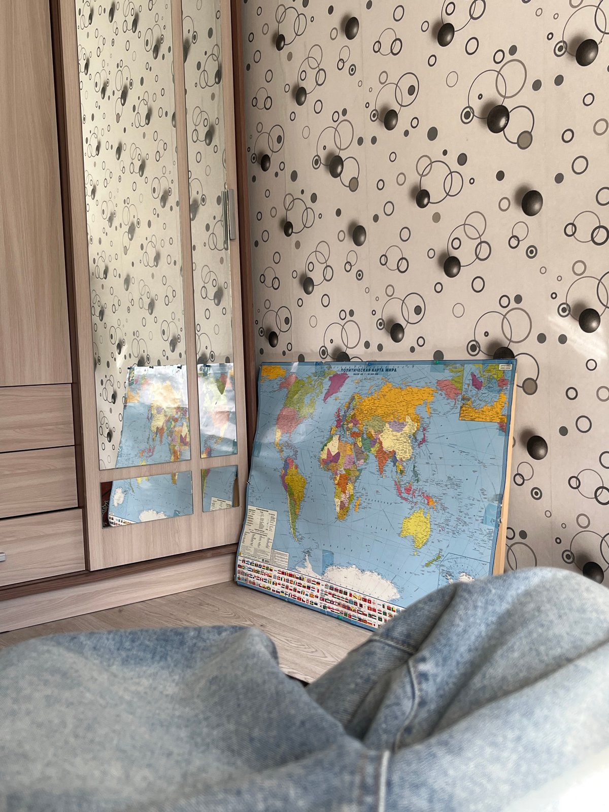 World map and mirrored dresser captured in indoor setting