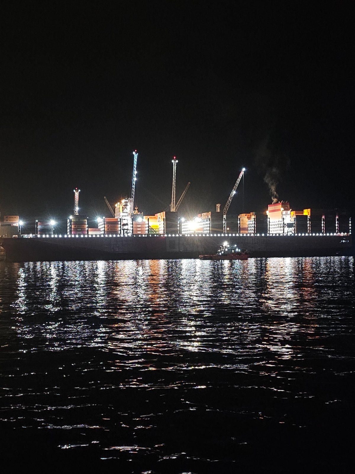 Late-night waterfront hangout with a cargo ship backdrop in Iquique