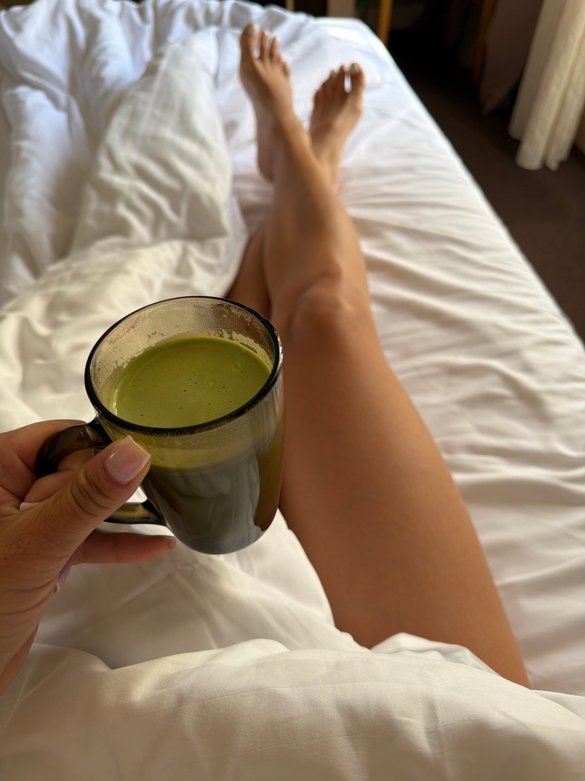 Person holds green beverage in bed, Svetlogorsk morning
