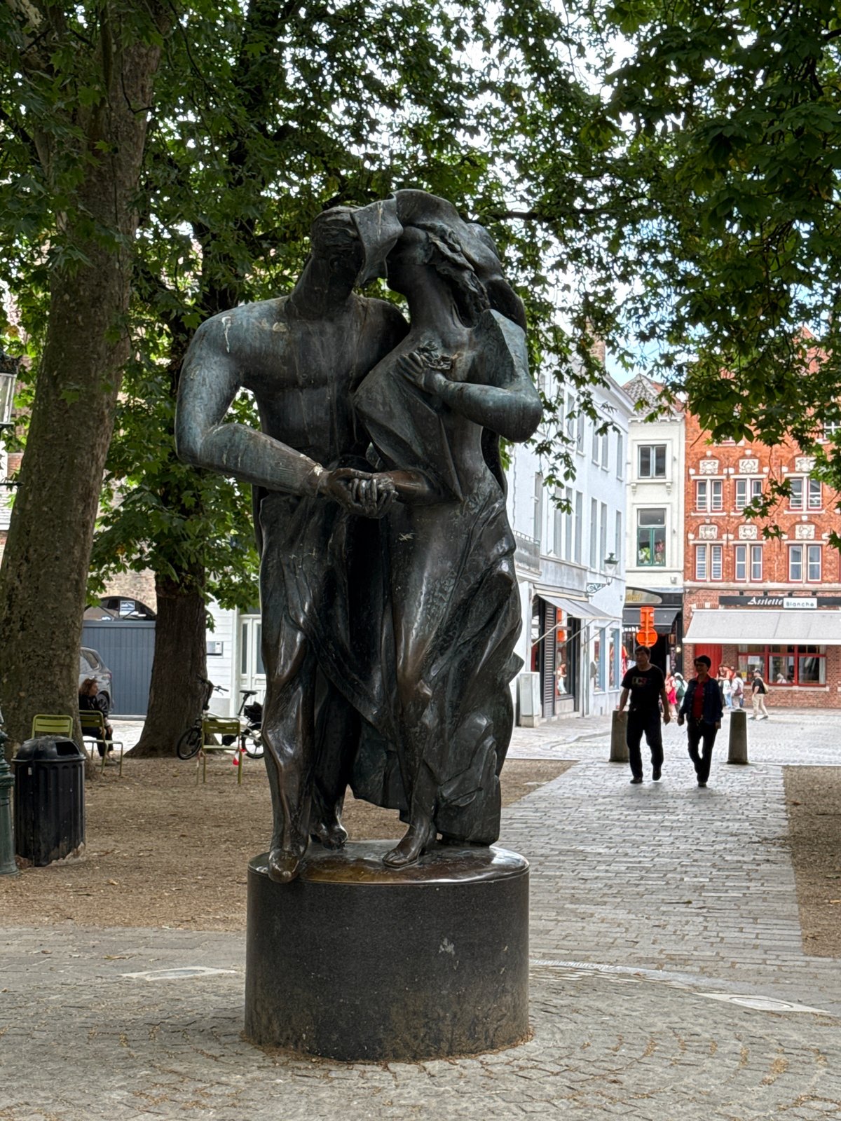 Street-level moments around a bronze sculpture in central Bruges