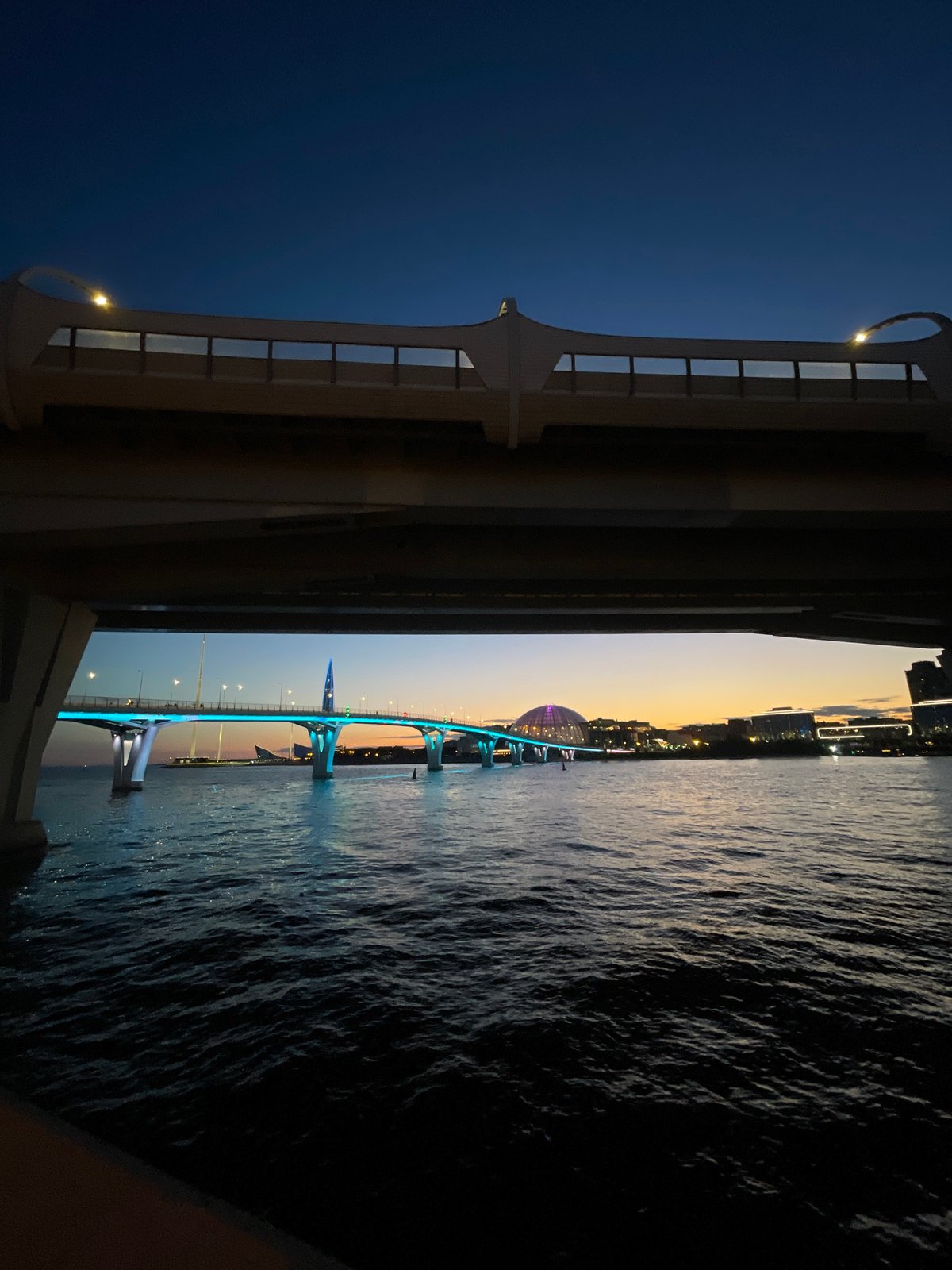 Car scene gathering under a blue-lit bridge at dusk