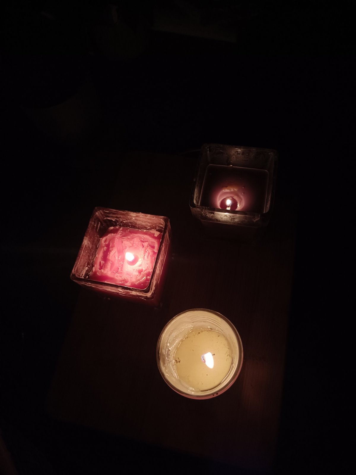 Three decorative candles lit on dark surface in Plovdiv