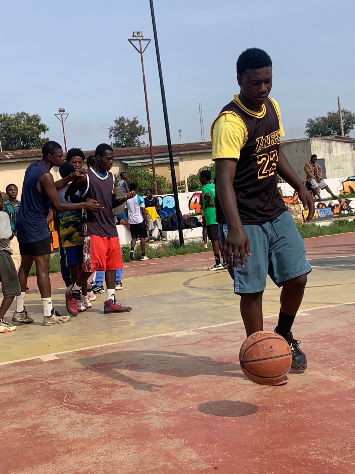 Pickup basketball on a red-and-yellow court in Gura Top, Nigeria.