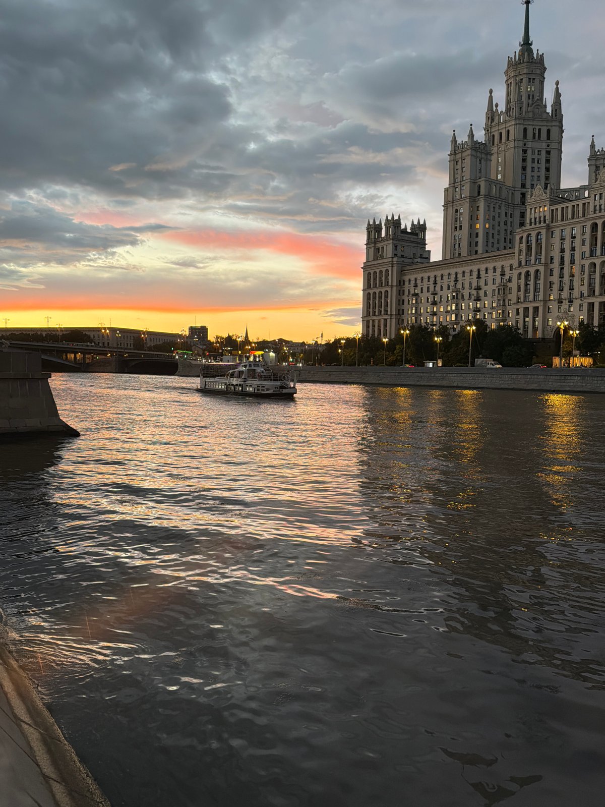 Moscow riverside at golden hour, Stalinist tower and stormy sunset sky