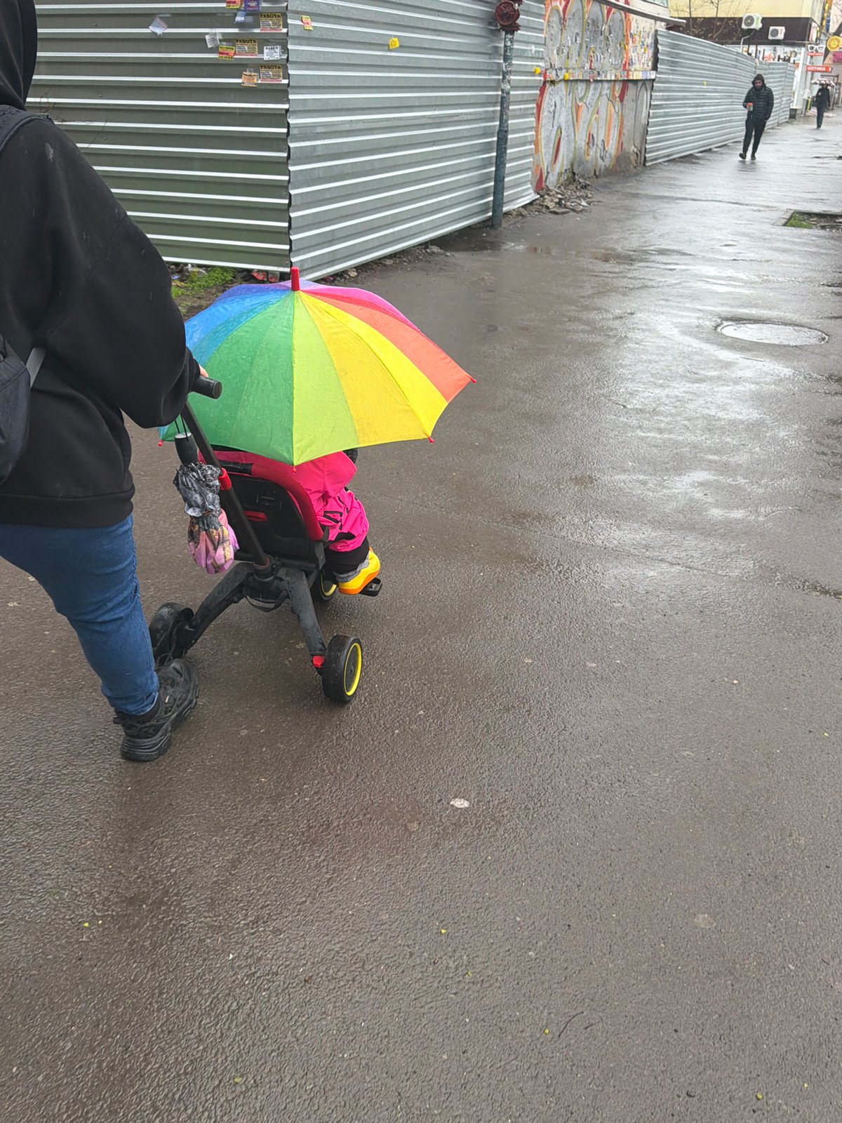 Parent walks baby in rain with rainbow umbrella, Rostov-on-Don