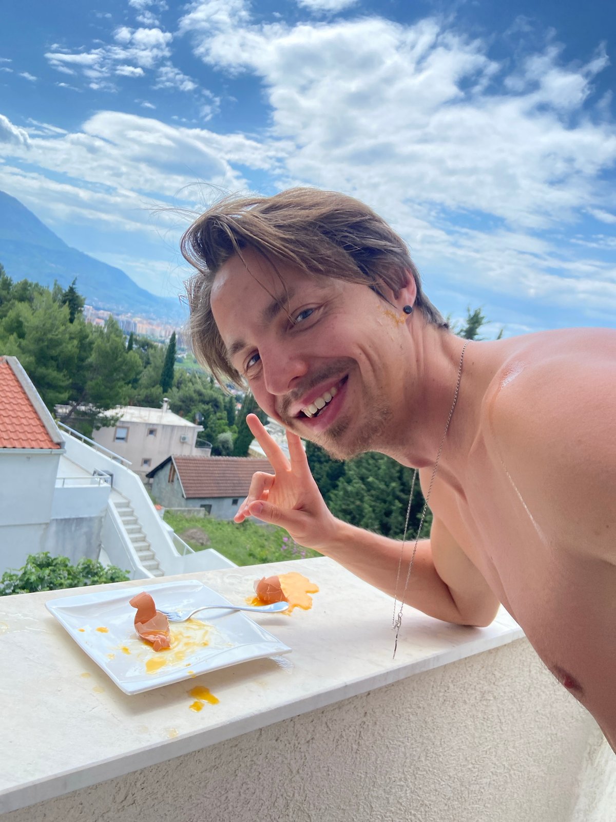 Man poses for skincare content on Montenegro balcony