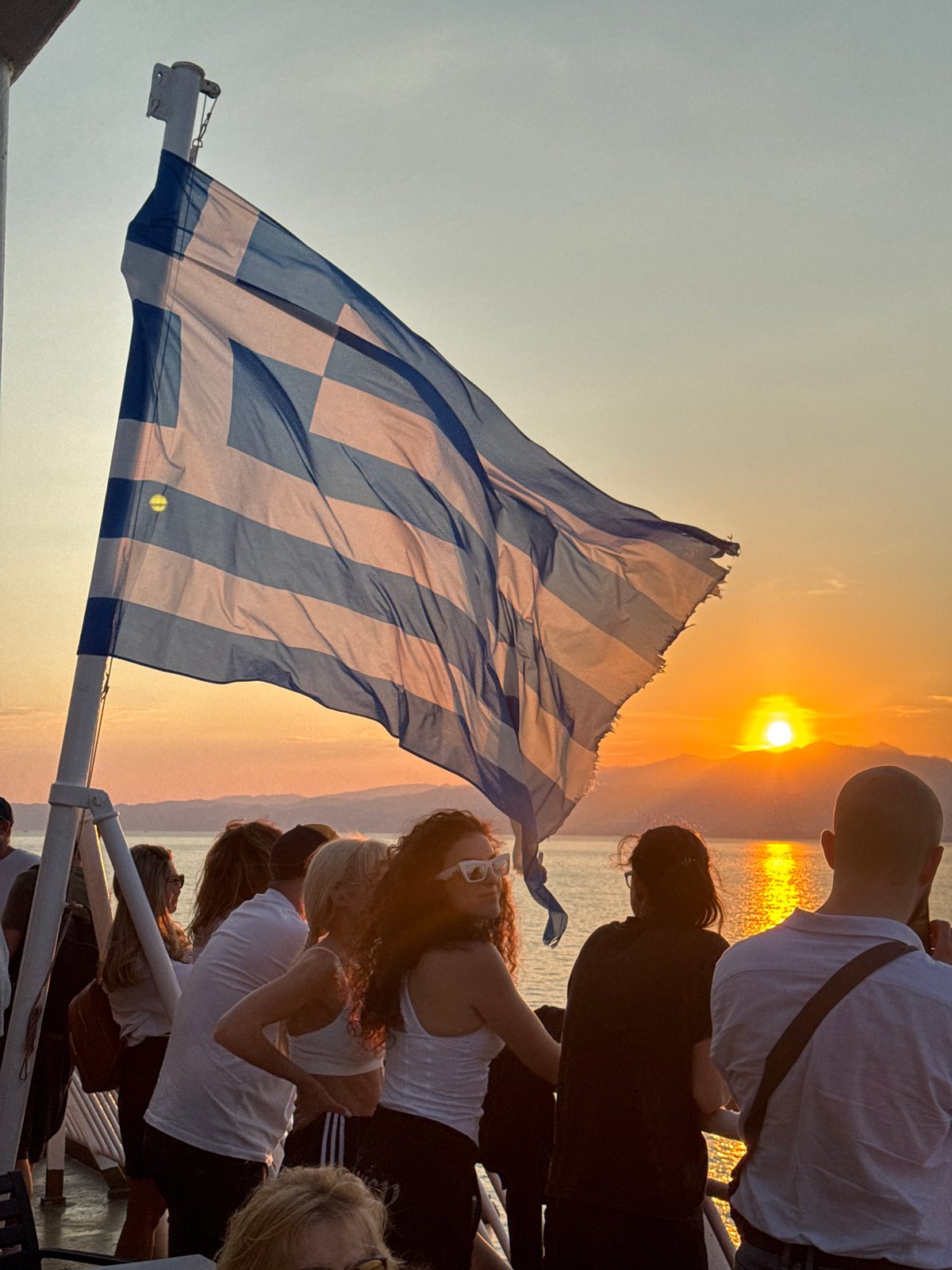 Greek flag flying on a boat at sunset near Kavala