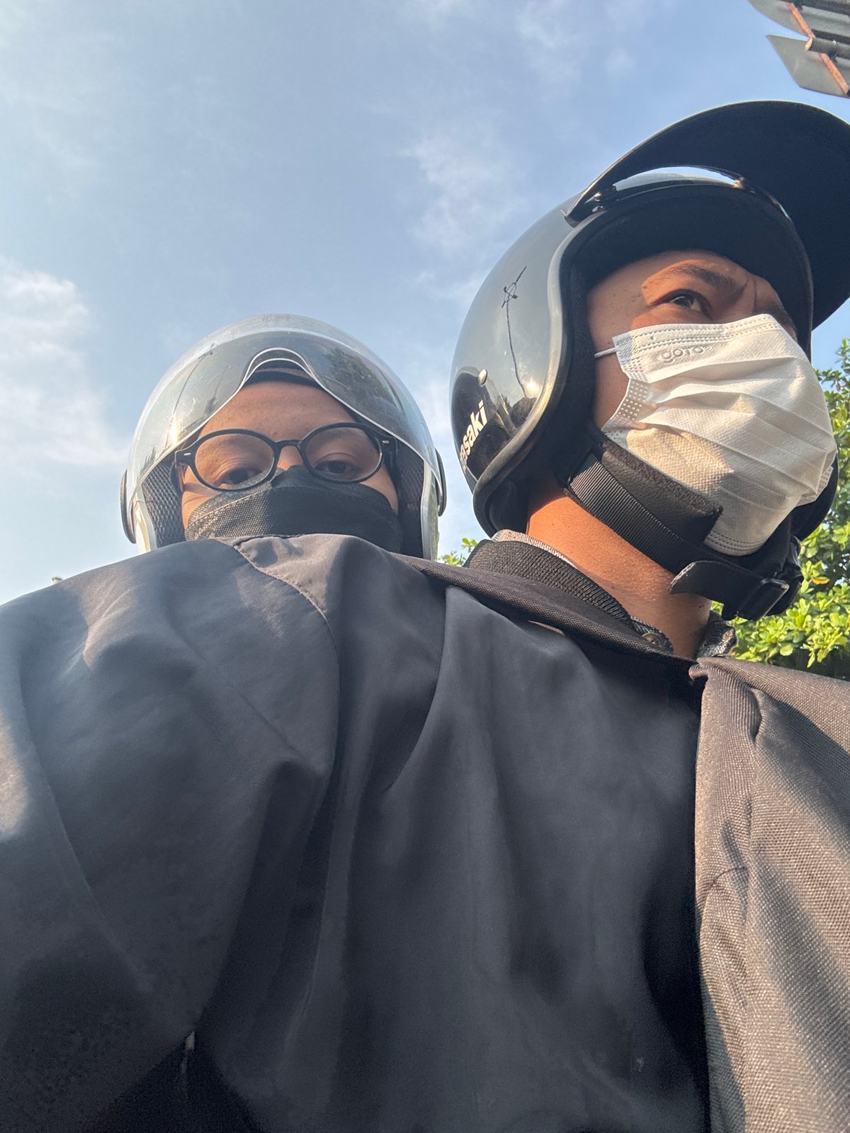 Masked motorcyclists pause at a West Jakarta traffic light