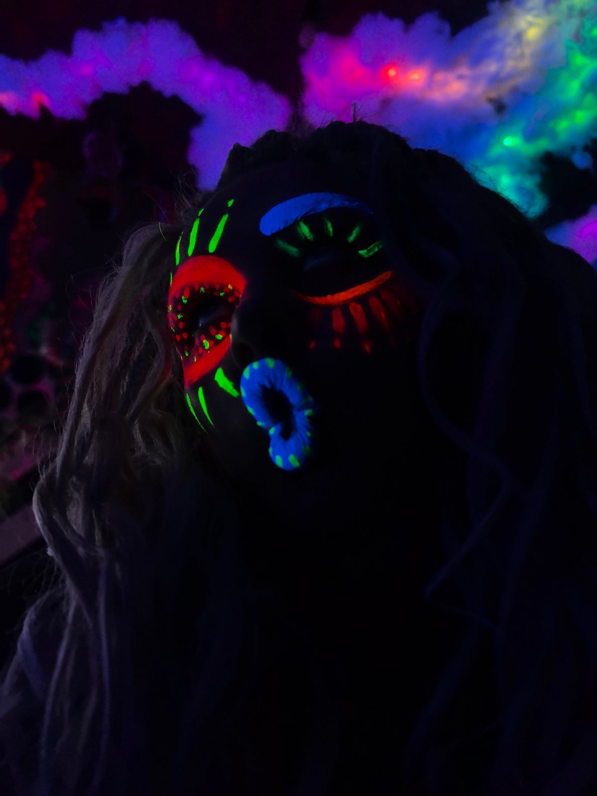 Neon face paint glows under blacklight at a night event in Russia