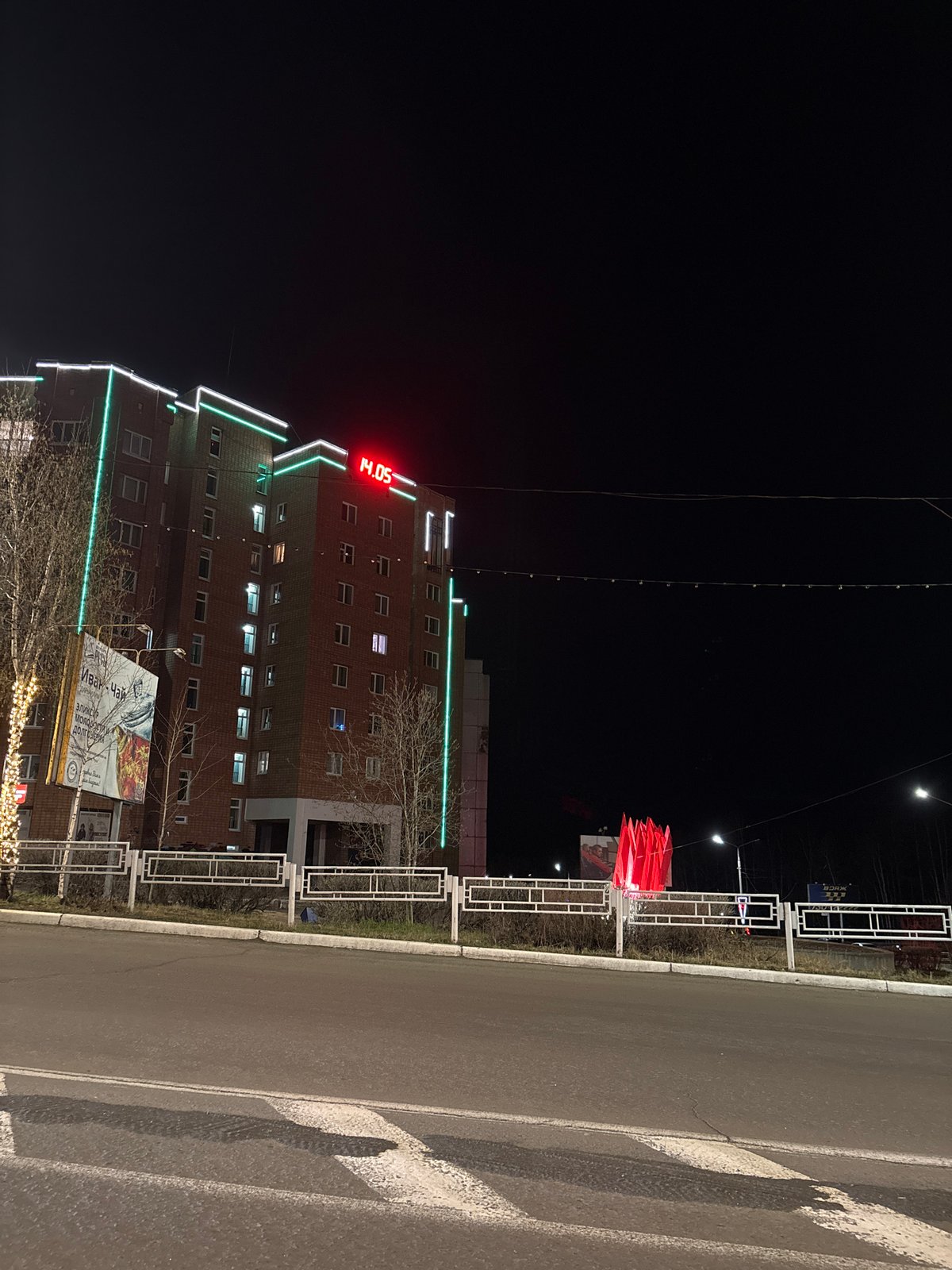 Green-lit building displays digital clock in Ust-Ilimsk nightscape