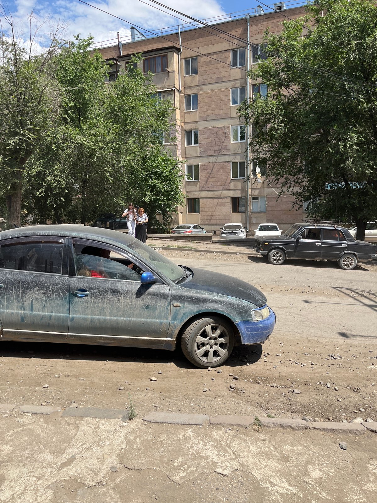 Dusty road traffic on an unpaved street in Gladzor, Armenia