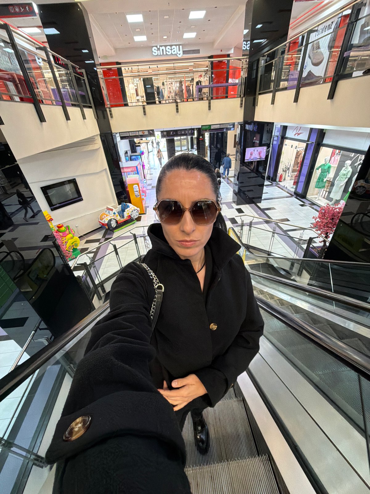 Woman in black coat spotted on mall escalator in Pleven
