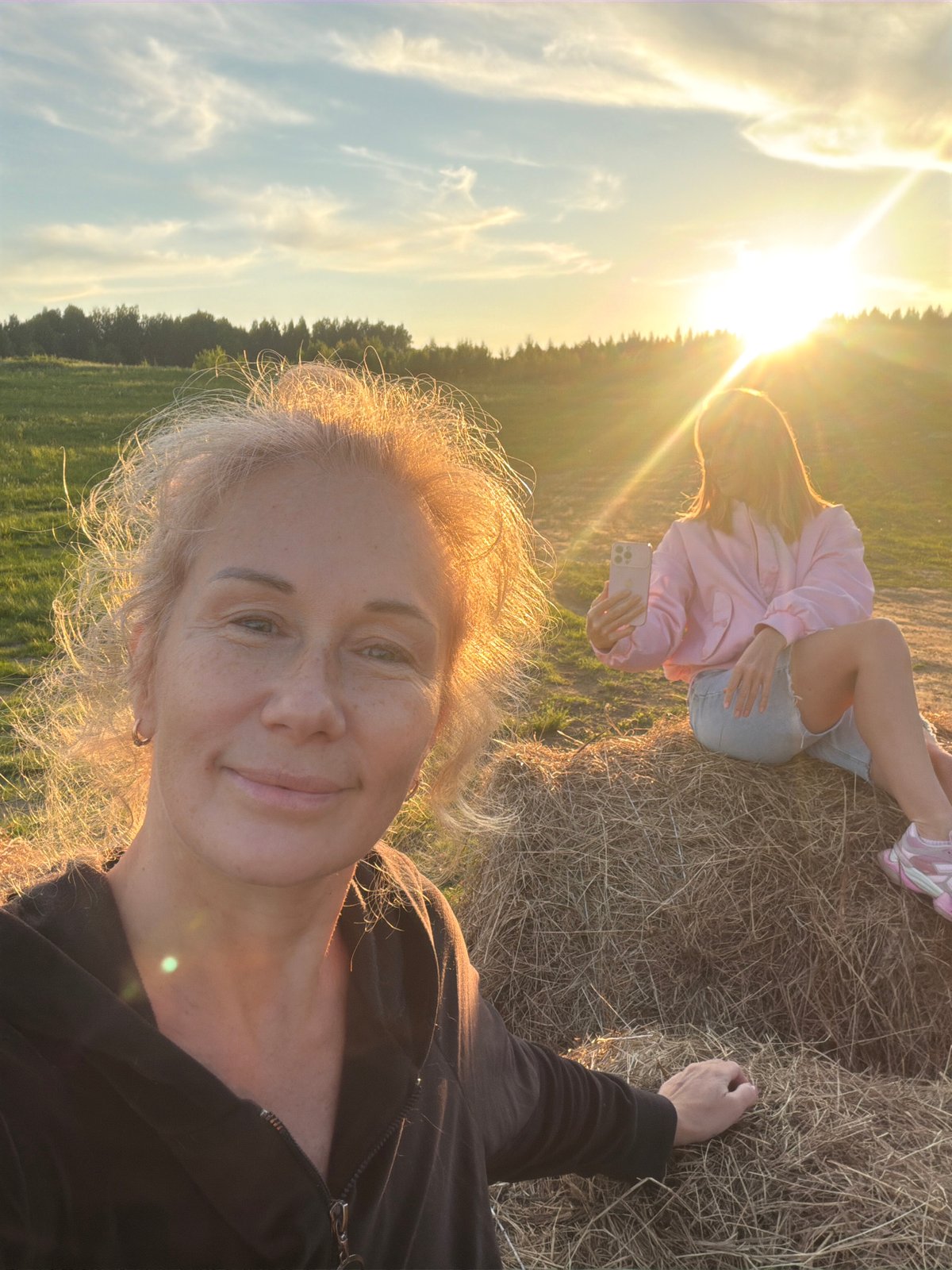Person walks through Russian field toward hay bales at sunset