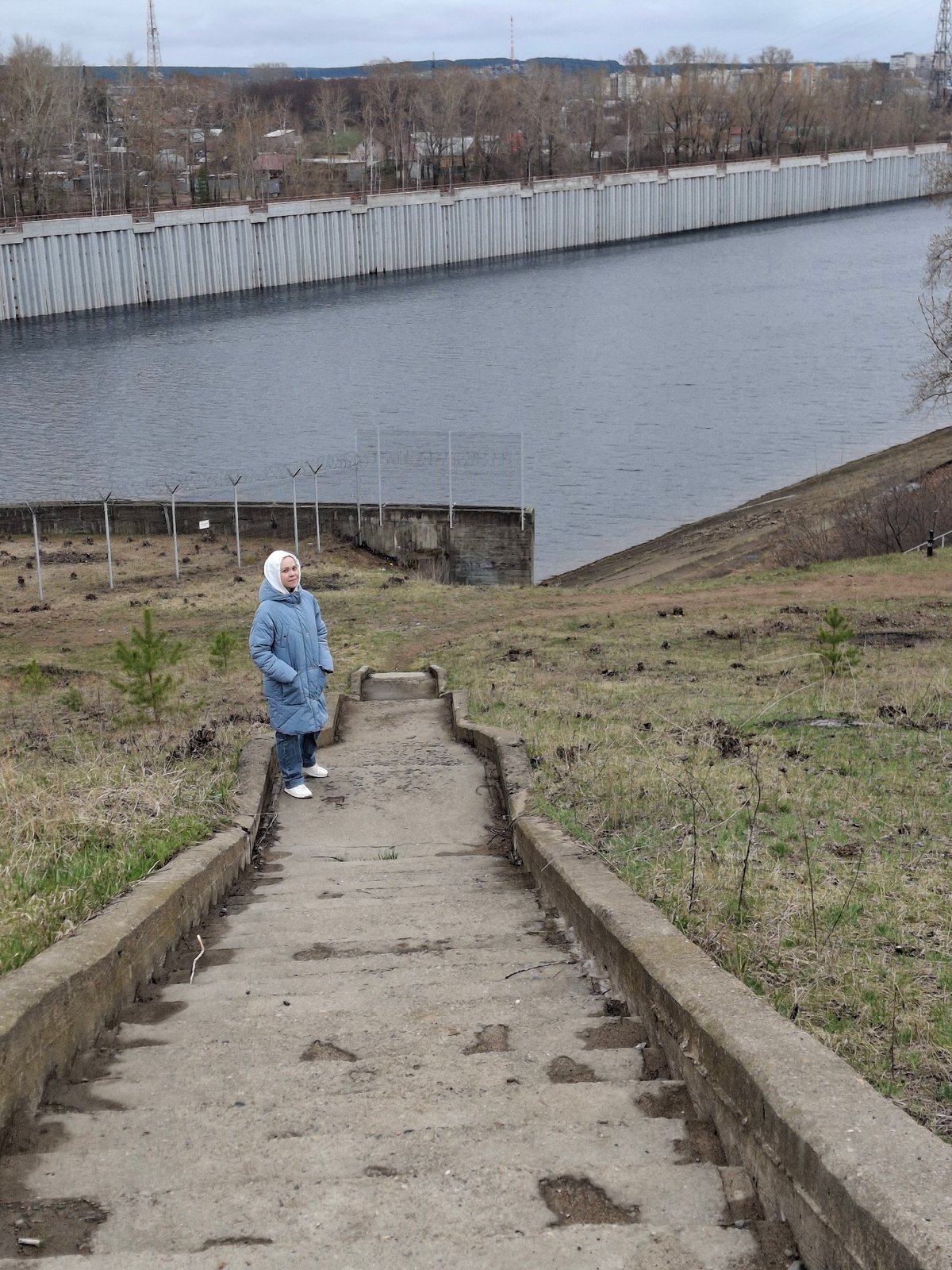 Woman walks waterside pathway in Chaikovsky, Russia
