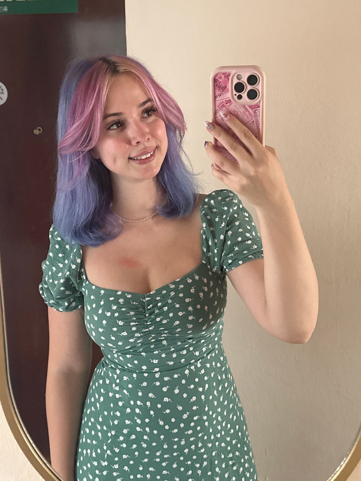 Woman takes mirror selfie in colorful hair, floral dress