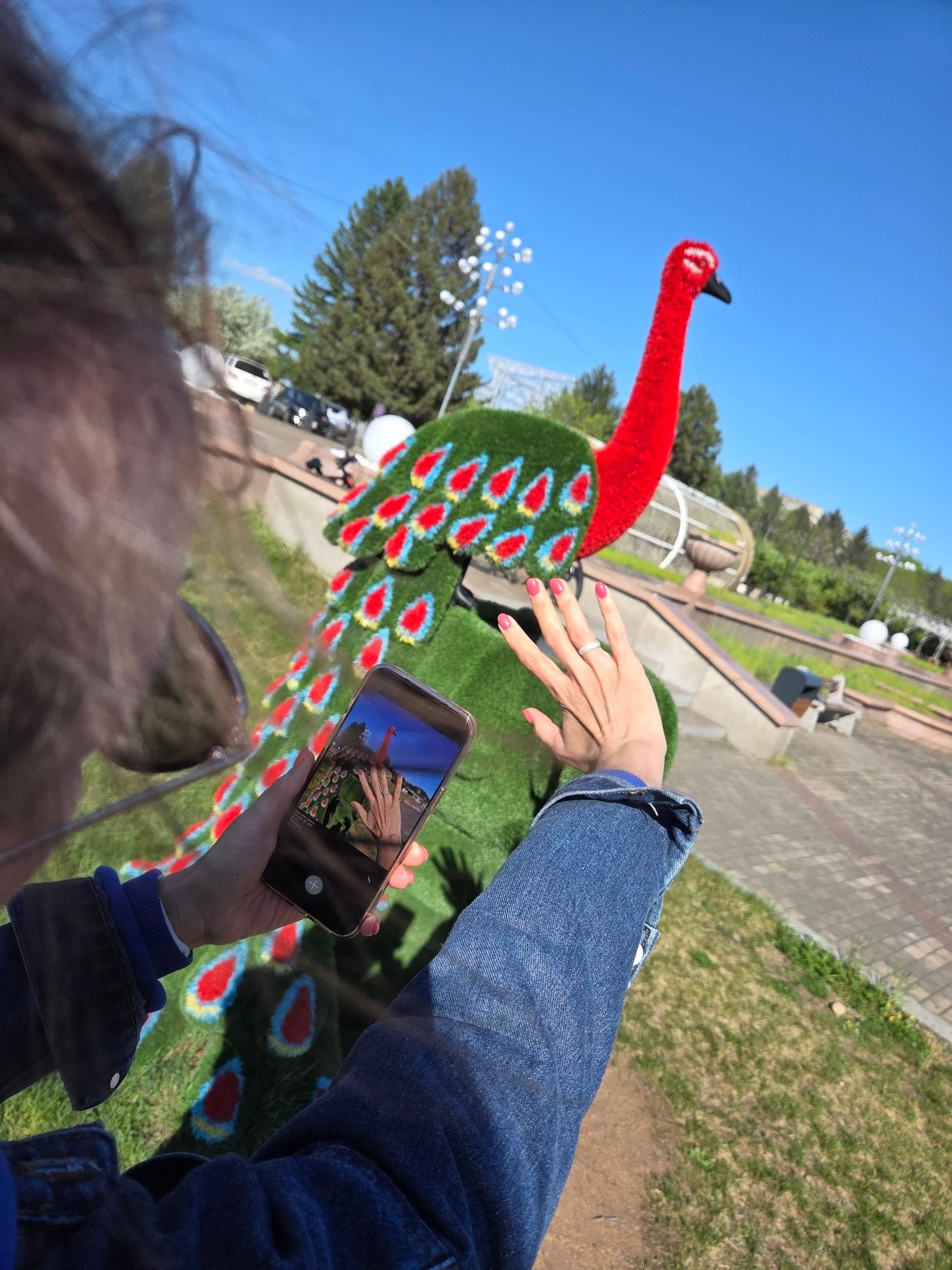 Woman poses with peacock topiary in Birobidzhan park