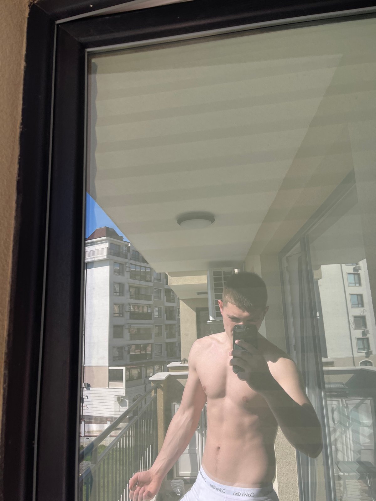 Window reflection captures smartphone user in Varna residential area