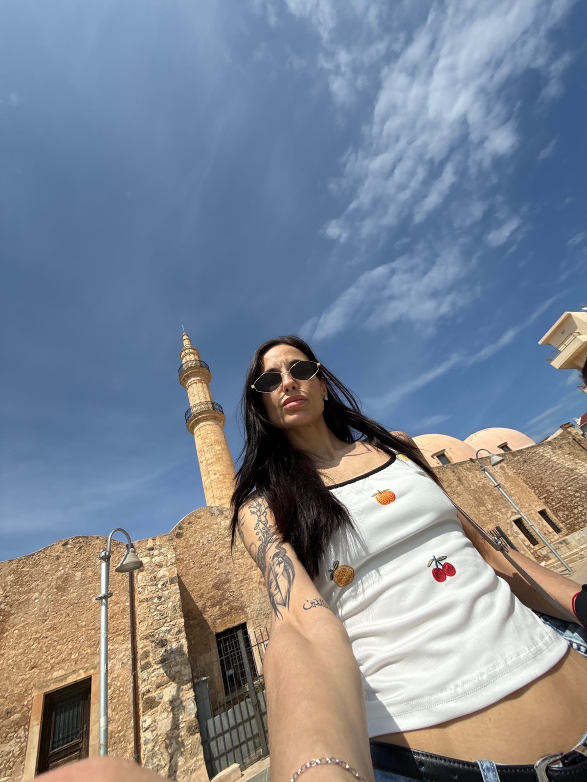 Woman rests near historic Venetian lighthouse in Rethymno waterfront