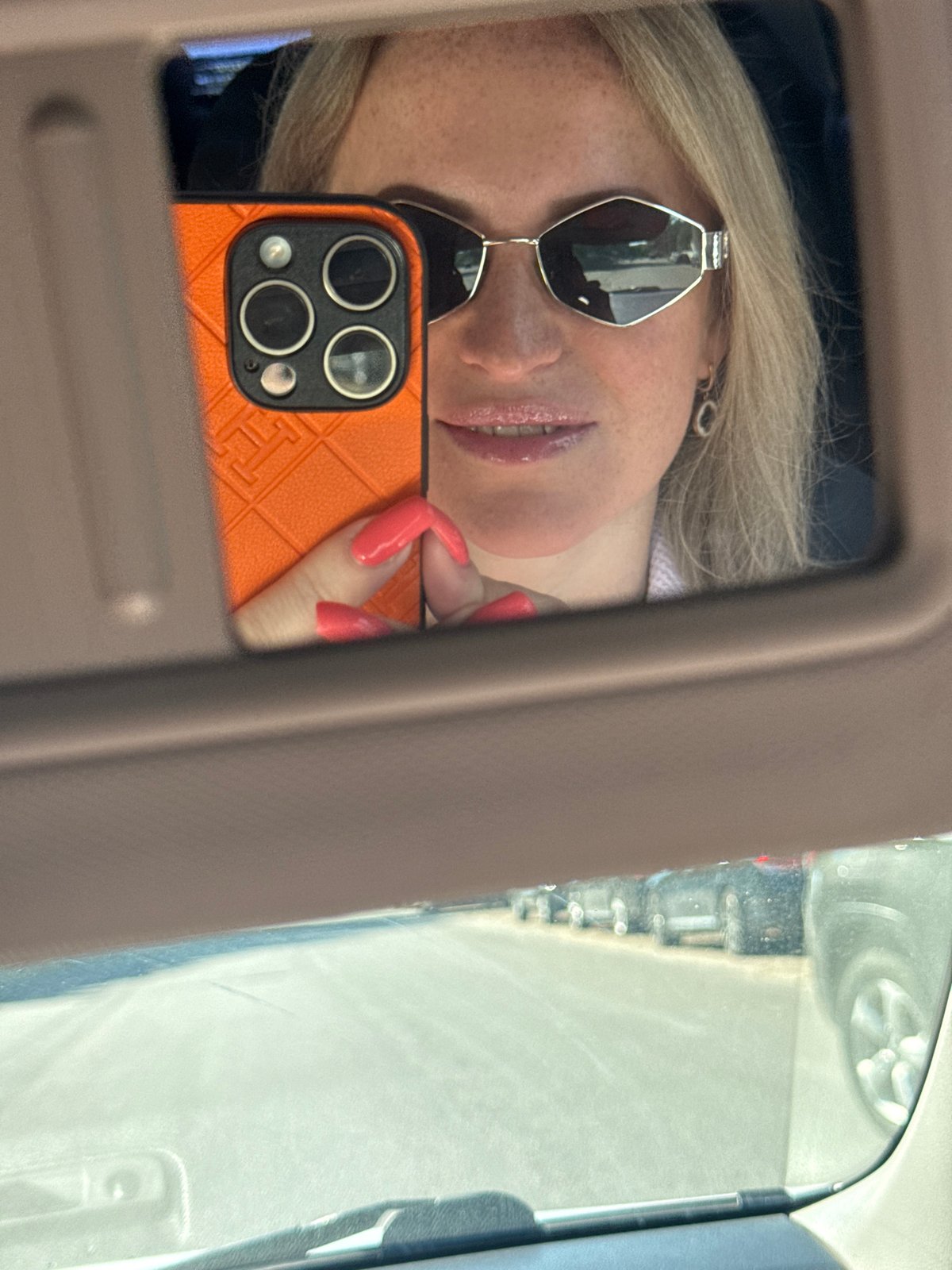 Car visor mirror reflection with phone in hand, Dnipro